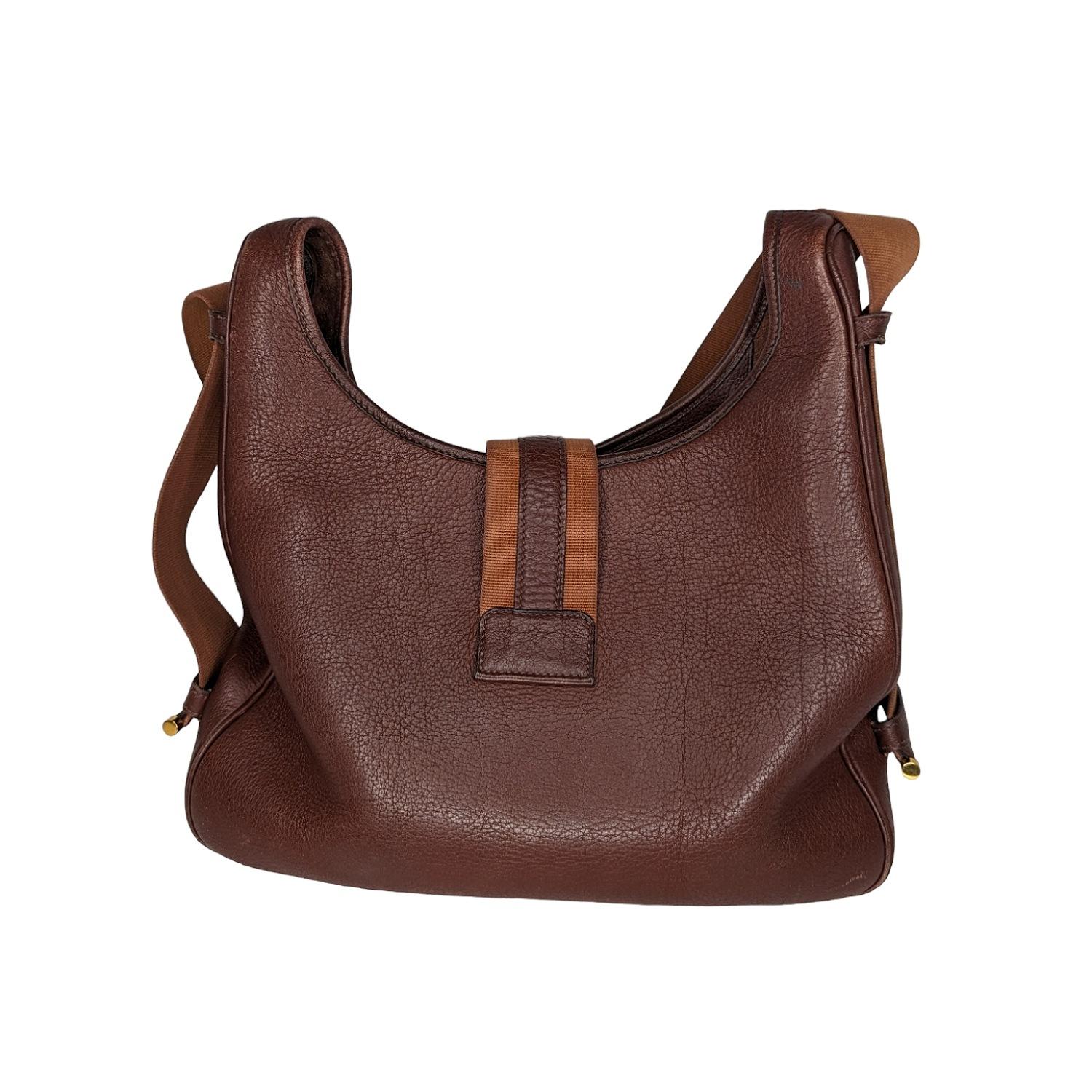 This stylish shoulder bag is beautifully crafted of brown leather. The bag features a looping canvas shoulder strap with polished gold hardware and a crossover strap with a gold latch. This opens to a spacious interior. This is a marvelous shoulder
