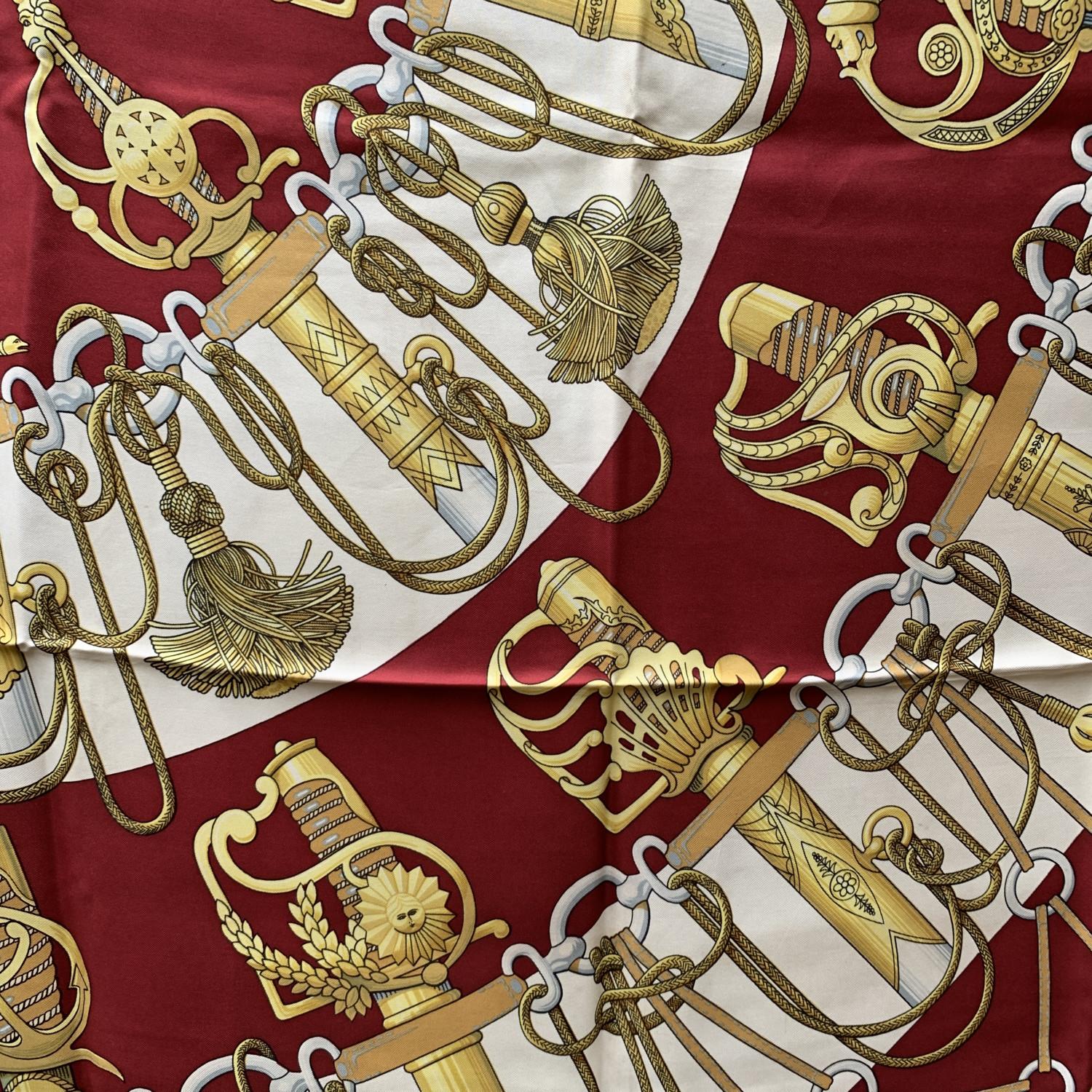 HERMES silk scarf named 'CLIQUETIS', designed by Julie Abadie and issued the first time in 1972. It features sword hilts, tassels and horsebit designs. It has re-issued many times, in different colours, formats and variations of. Hand rolled edges.