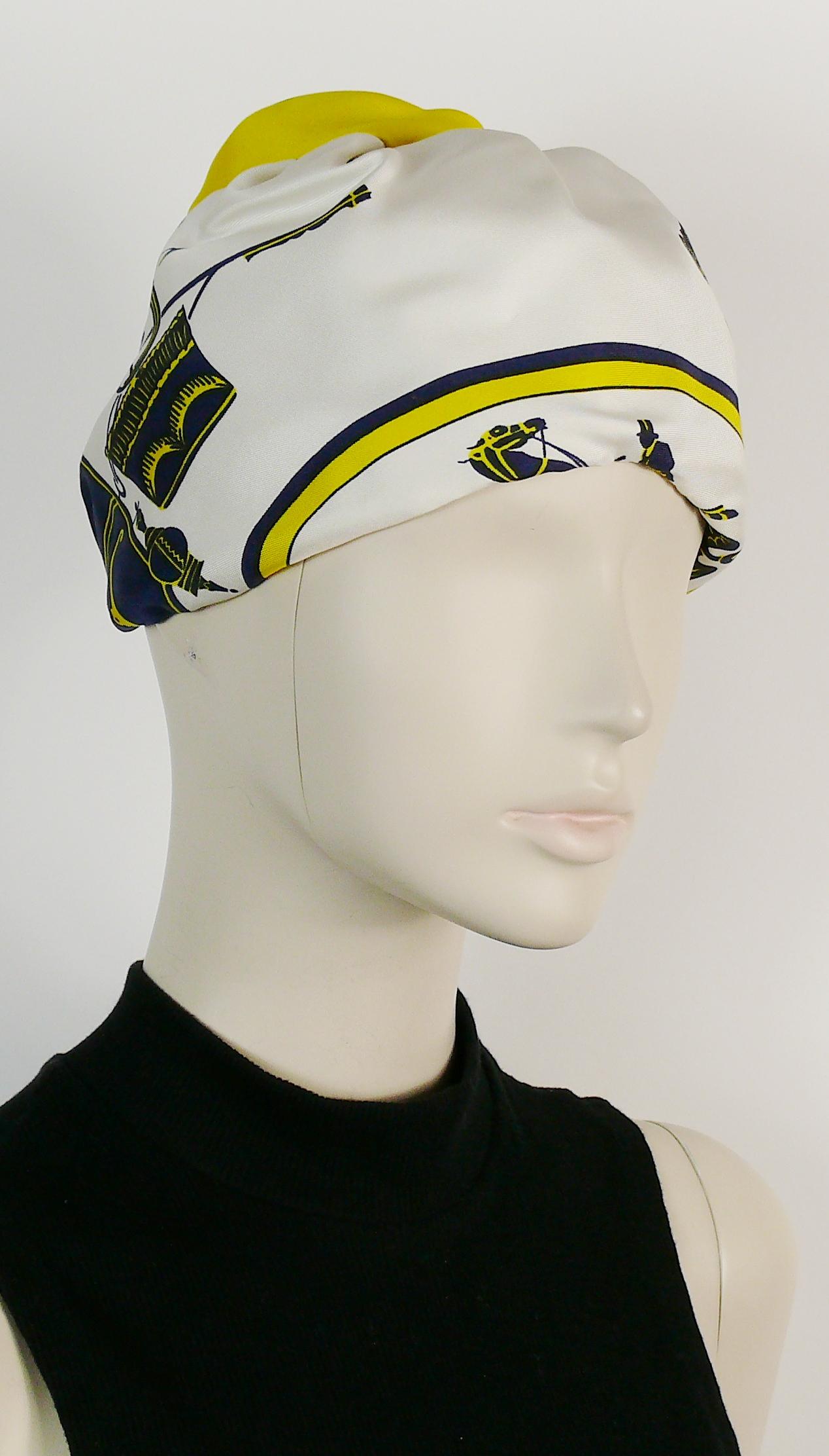 HERMES vintage silk turban hat printed with carriages in shades of blue and yellow on an off-white background.

Netted interior.
Grosgrain headband.
Elasticated neckline.

Label reads HERMES Paris.

Indicative measurements : circumference approx. 52
