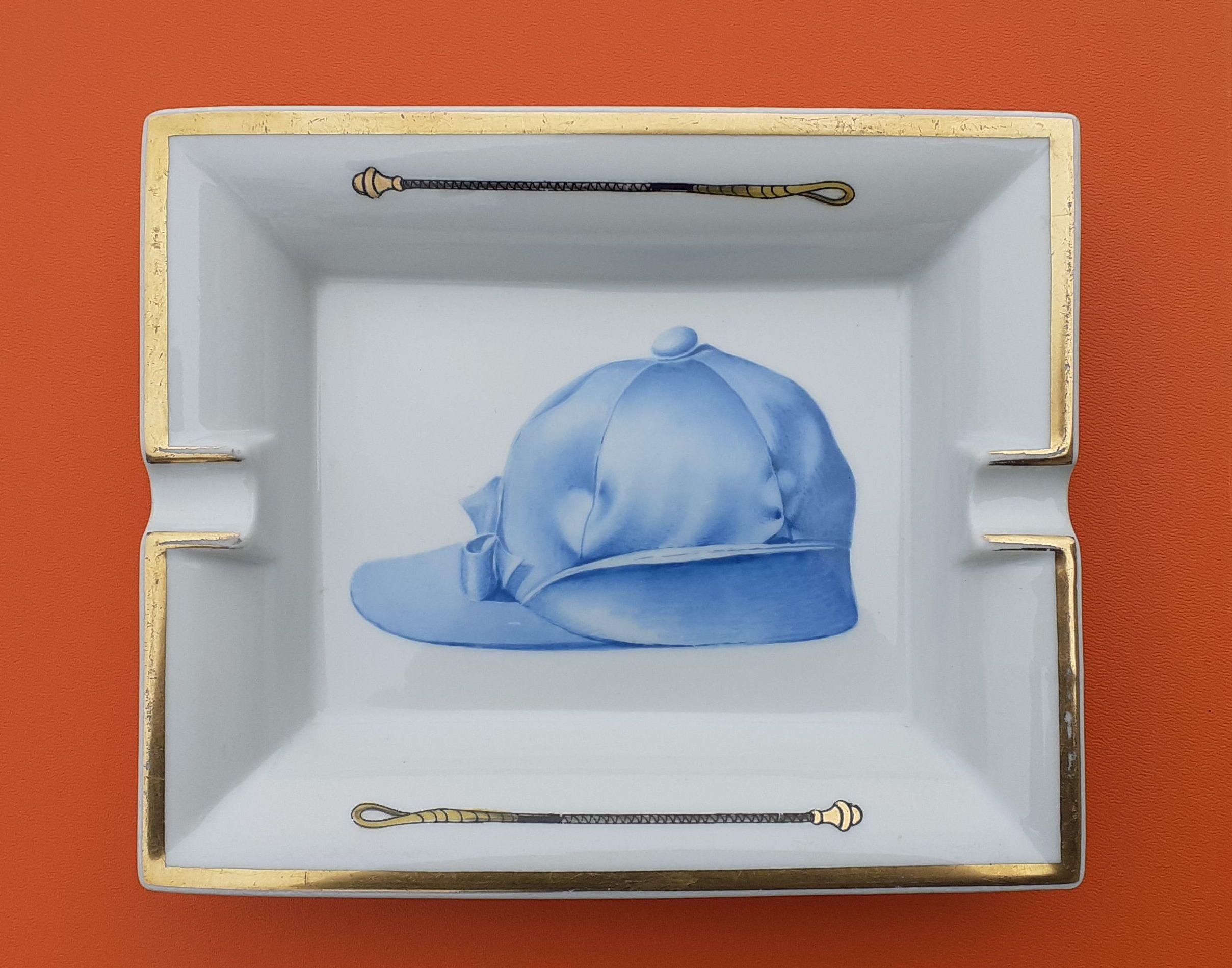 Rare and Beautiful Authentic Hermès Ashtray

Pattern: Riding helmet / Jockey cap

Made in France

Made of printed porcelain and golden edges

Bottom covered with blue-green leather

Colorways: White, Blue, Golden

