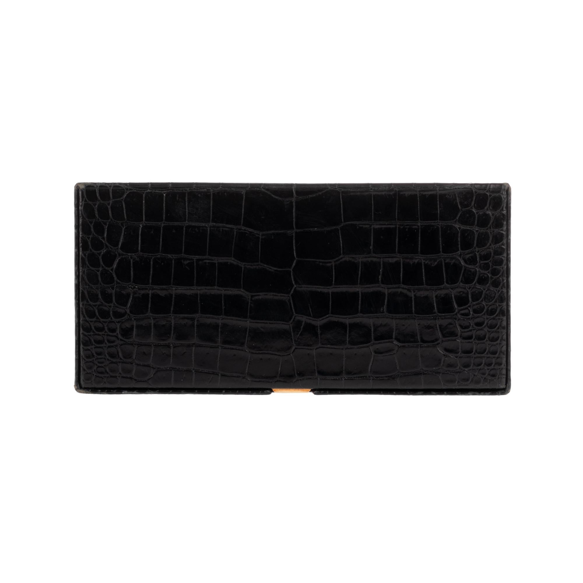 Hermès Vintage rectangular cigarette box in black crocodile.
Gold plated metal coupling.
Opening by press clasp on the hood.
Interior: 2 cigarette compartments with black leather strap to hold cigarettes.
