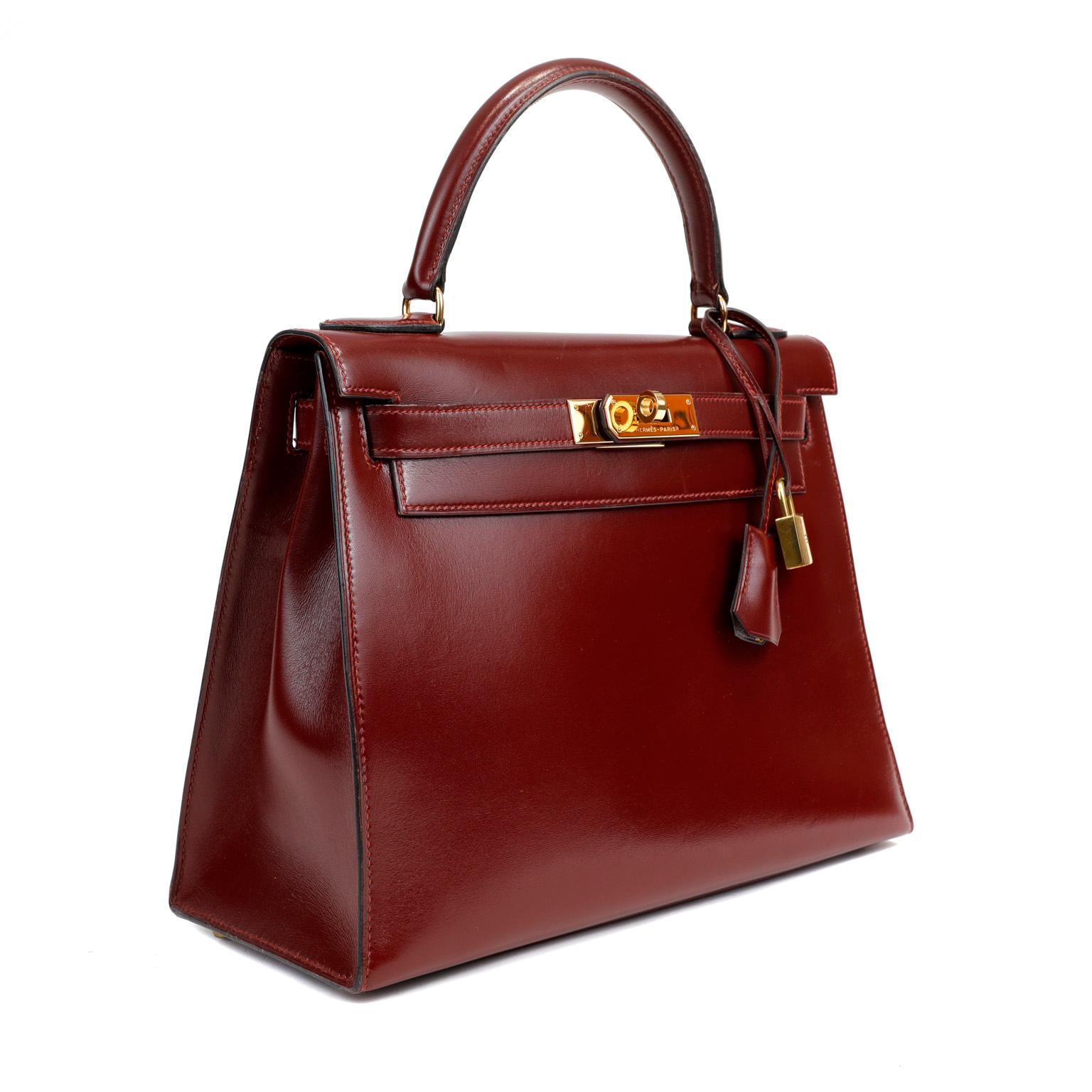 This authentic Hermès Dark Red Box Calf 28 cm Kelly is in excellent vintage condition. Hermès bags are considered the ultimate luxury item worldwide. Each piece is handcrafted with waitlists that can exceed a year or more. The demure Kelly is