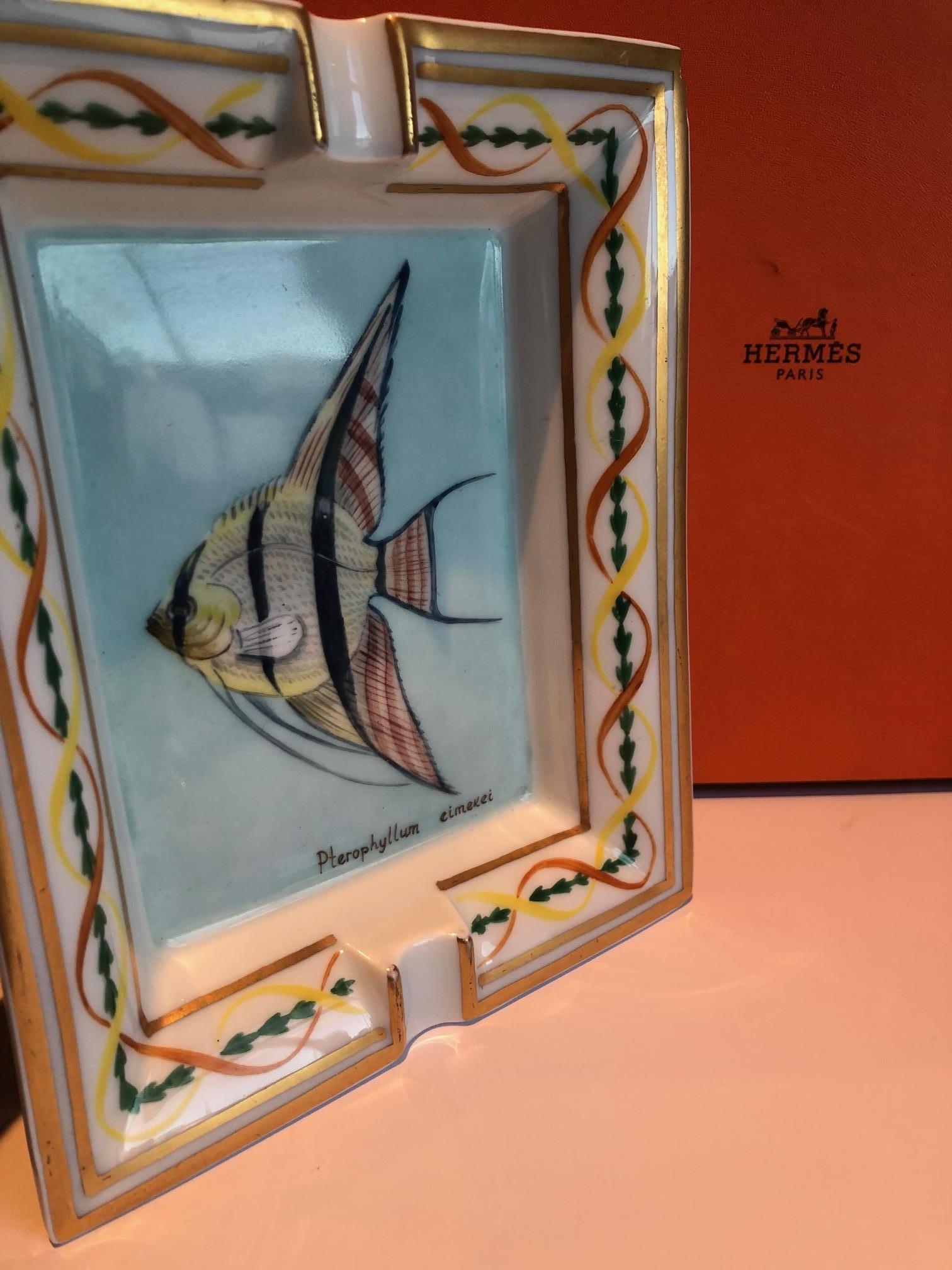 HERMÈS Vintage Flying Fish Porcelain 24 k Gold plated Ashtray W/Box C.1990s

Hermès  Porcelain ashtray with flying fish decors. Hand brush printed with 24 k gold plated with rich thick gold  tone stripes, multi colour arabesque with a flying fish, 