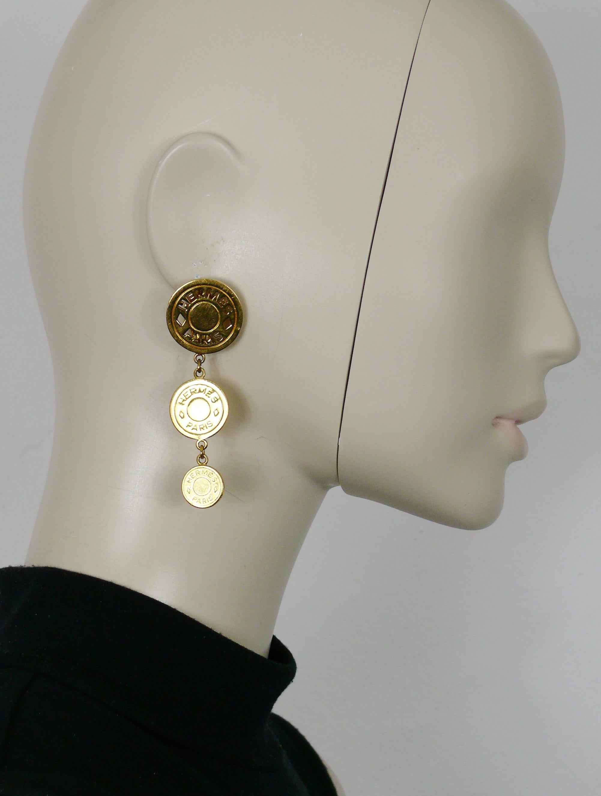 HERMES vintage gold tone dangling earrings (clip on) featuring three graduated clou de selle coins with cut-out and embossed HERMES PARIS logos.

Embossed HERMES PARIS Bijouterie Fantaisie.

Indicative measurements : max. height approx. 7.4 cm (2.91