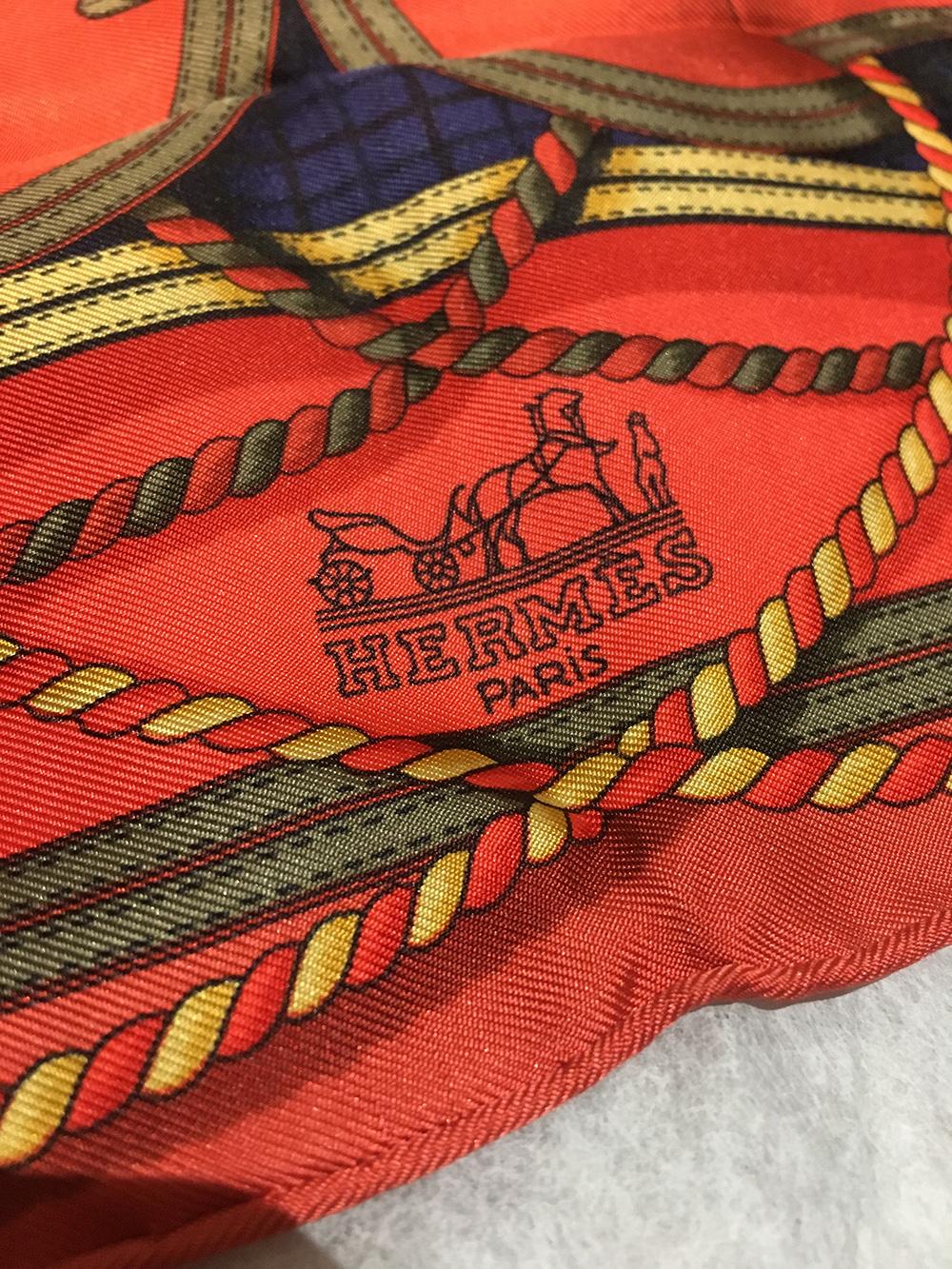BEAUTIFUL Vintage Hermes Grand Tenues silk pocket square in excellent condition. Original silk screen design c1985 by Henri d'Origny features a regal ribbon and crown design over an orange background surrounded by navy and gold accents. 100% silk,