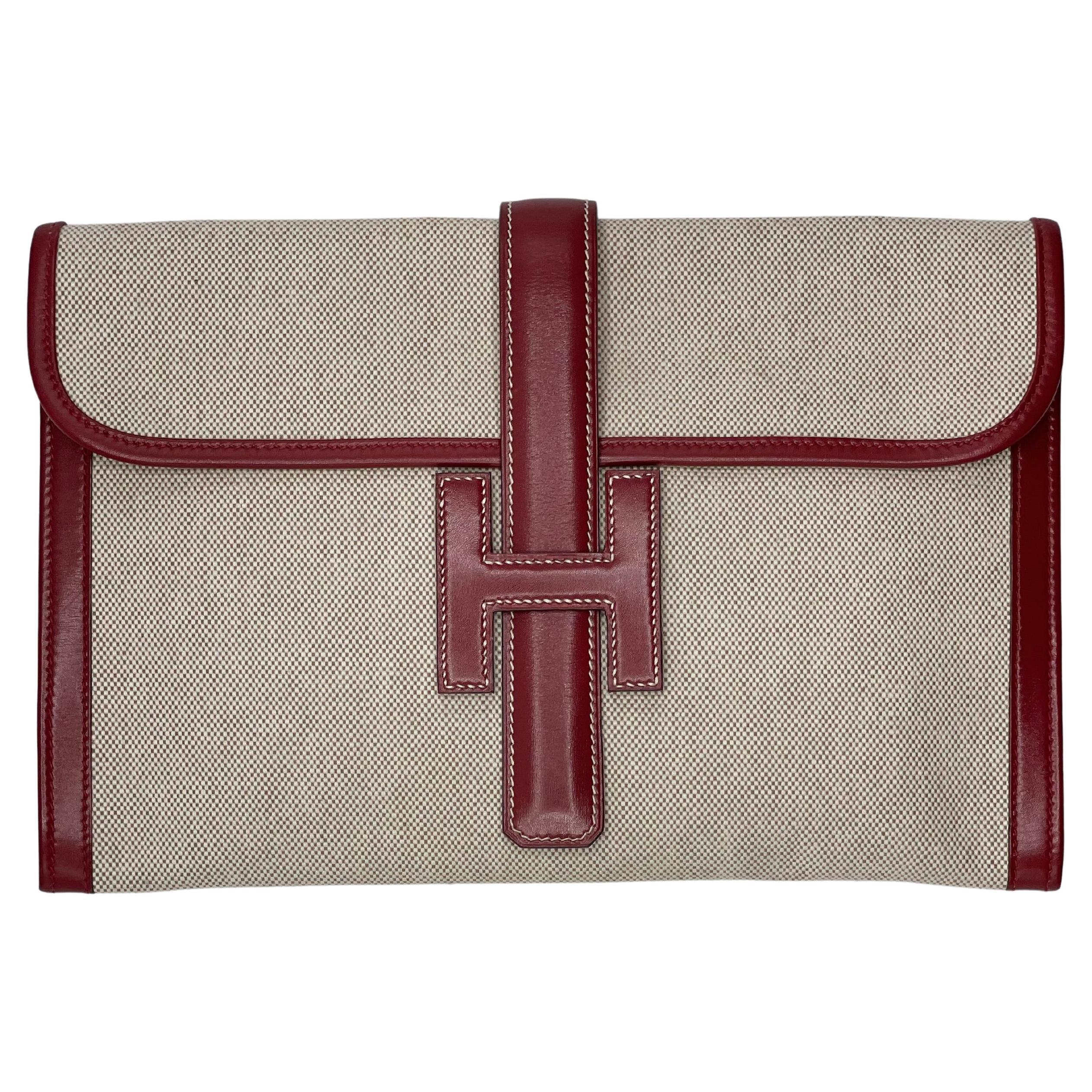 Hermès vintage jige toile leather trim clutch 29. Light beige canvas framed by burgundy leather, with beige stitching on the leather closure. This 1988 clutch has light stains on the inside but is otherwise in good condition. No smell 