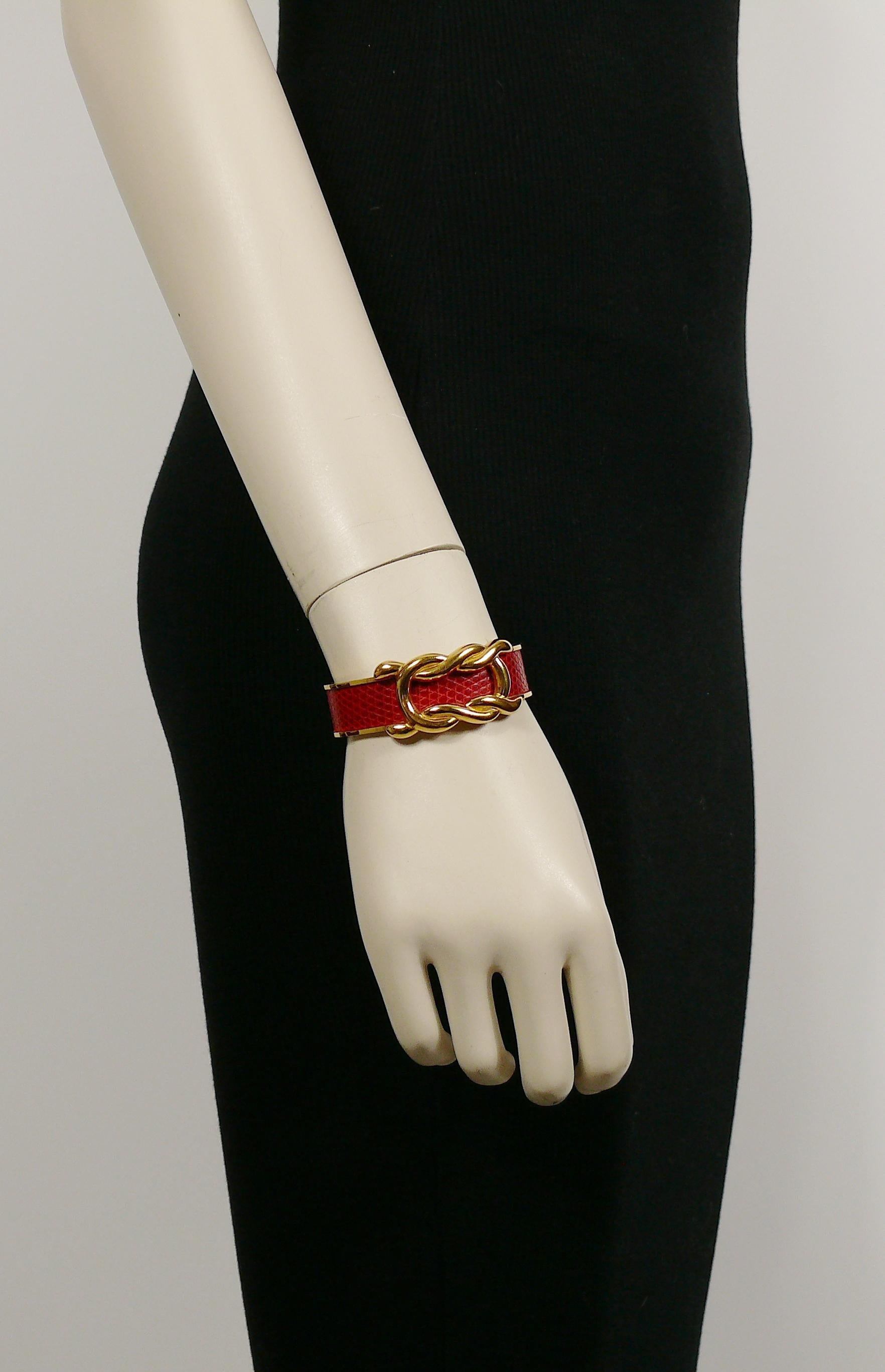 HERMES vintage gold toned and red leather cuff bracelet featuring a gorgeous knot design.

Embossed HERMES.
Maker's hallmark.

Indicative measurements : inner measurements 5.5 cm x 4.5 cm (2.17 inches x 1.77 inches) / max. width approx. 2.2 cm (0.87