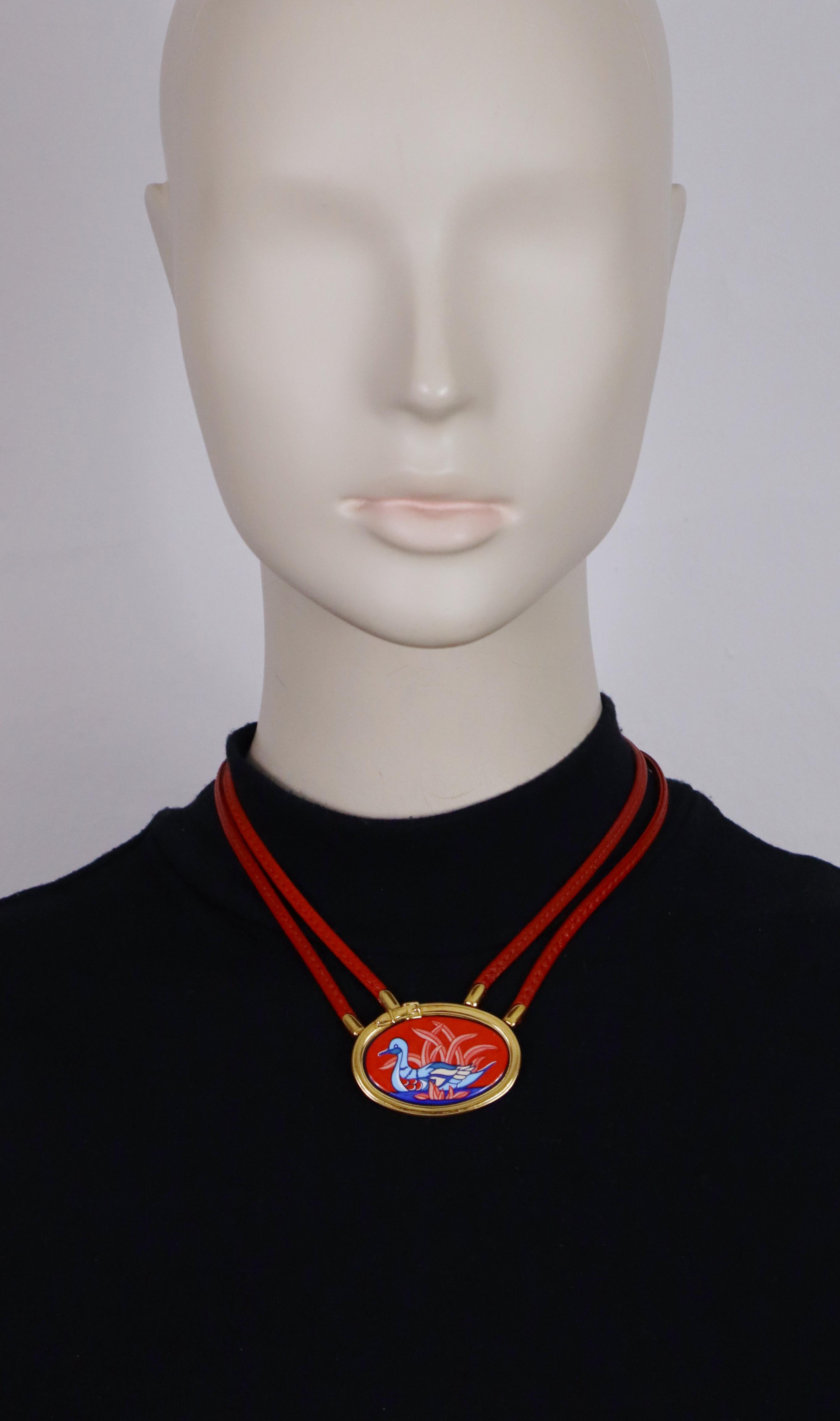Collana HERMES vintage in pelle rossa con medaglione in smalto multicolore.

Questa collana presenta un medaglione in tonalità oro con smalto multicolore raffigurante un'anatra e piante acquatiche su uno sfondo rosso, cinturini in pelle con