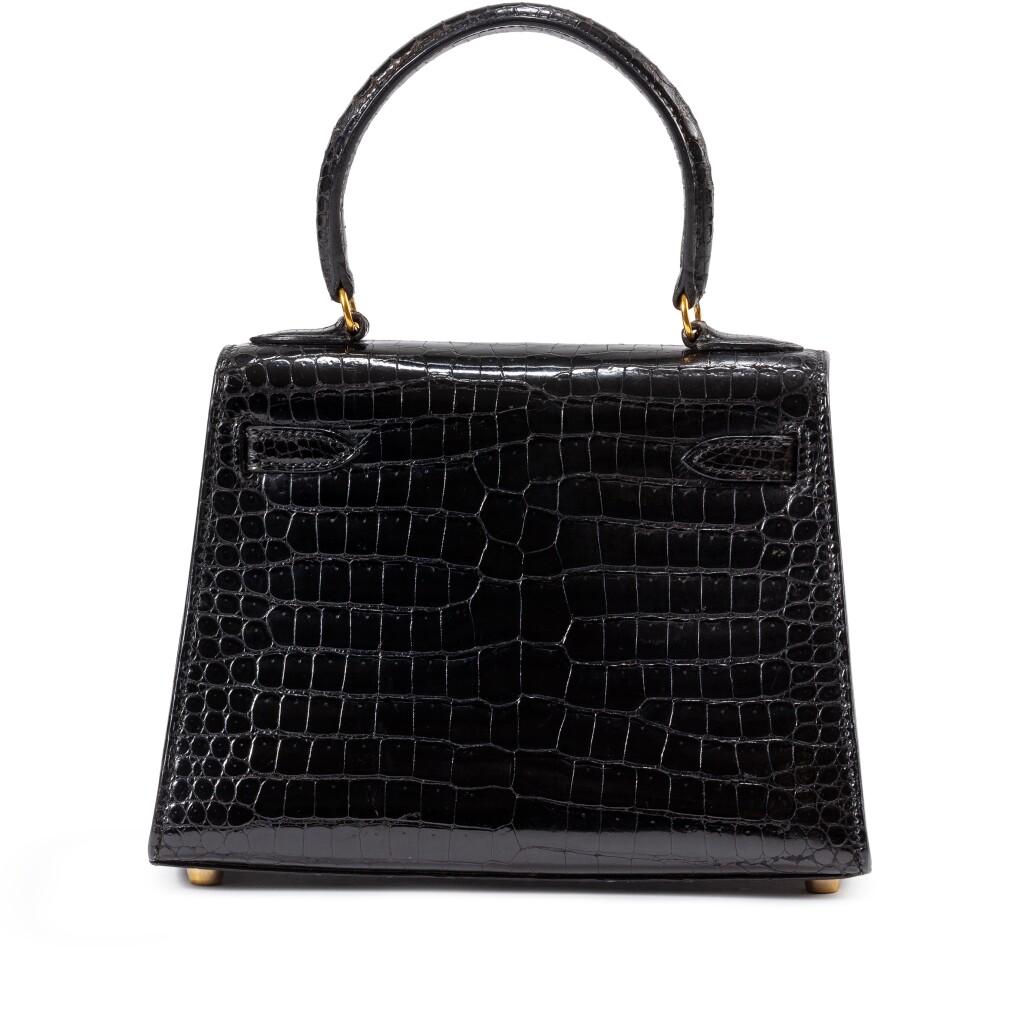 Experience timeless luxury with this exquisite vintage Mini Kelly 20 Sellier, crafted from sleek black shiny croc leather and finished with shimmering gold hardware. This rare piece from 1992 combines classic sophistication with a hint of opulence,