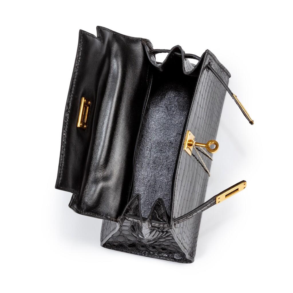 Erleben Sie zeitlosen Luxus mit dieser exquisiten Mini Kelly 20 Sellier im Vintage-Look. Sie ist aus glattem, schwarz glänzendem Krokoleder gefertigt und mit schimmernden, goldenen Beschlägen versehen. Dieses seltene Stück aus dem Jahr 1992