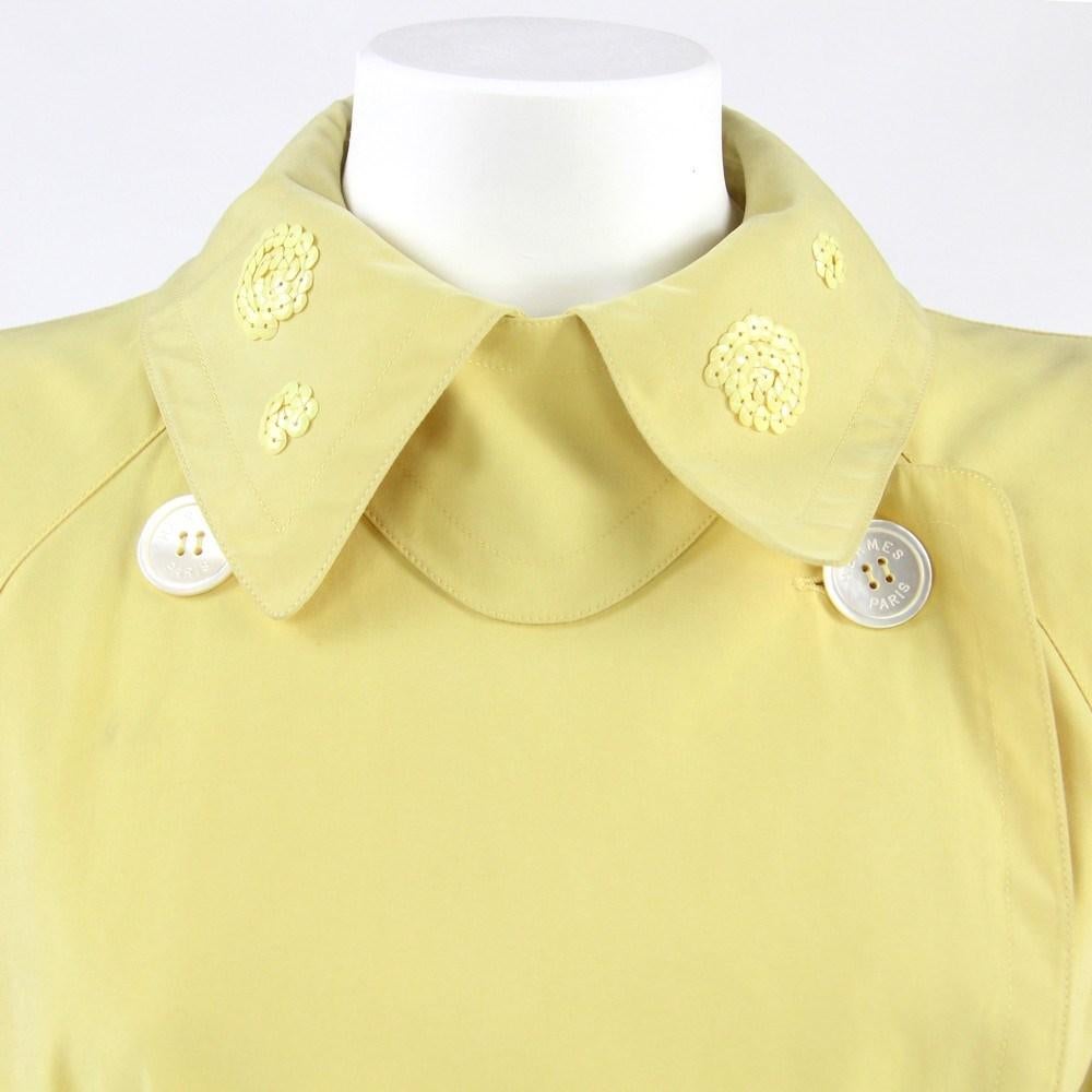 Hermès pastel yellow 80s mid-length upcycled trench coat with tone on tone sequins embellishments. Classic lapels collar, double breasted front fastening, long sleeves with strap and buckle at cuffs, belted waist and rear slit.

Size: 38 FR

Flat
