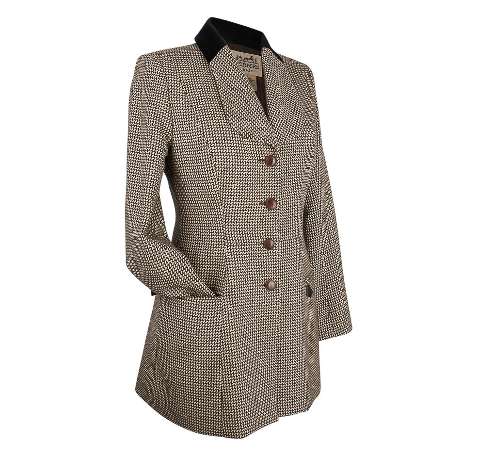Mightychic offers a  particularly beautiful 4 button single breasted Hermes vintage riding jacket.
Shawl shaped lapel with a black velvet collar.
Leather covered buttons.
The fabric is an elegant small pattern of black and chocolate brown on a cream