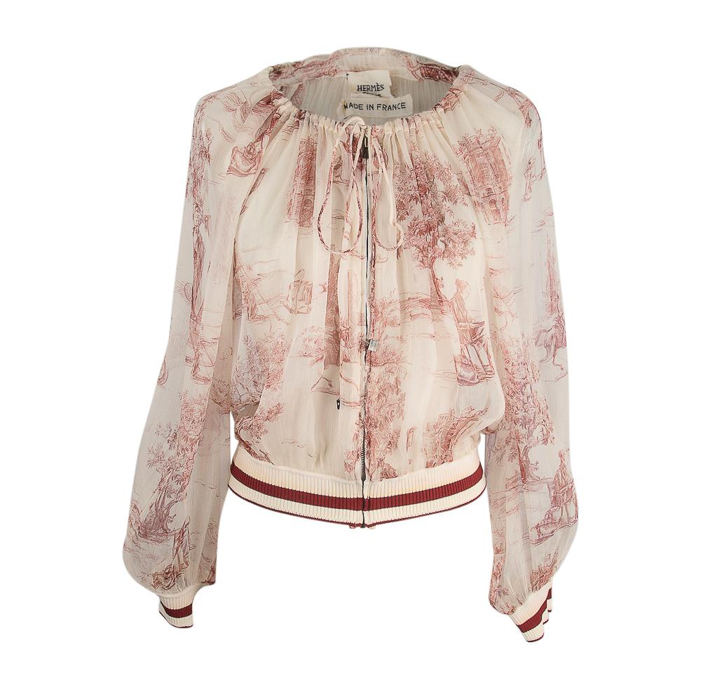 Guaranteed authentic Hermes vintage semi sheer and ultra light silk zip front jacket / top.
Beautiful blouson with a charming and idyllic print in cream and bordeaux.
Drawstring neckline with miniature rithenium locks at tie ends.
Cuffs and bottom