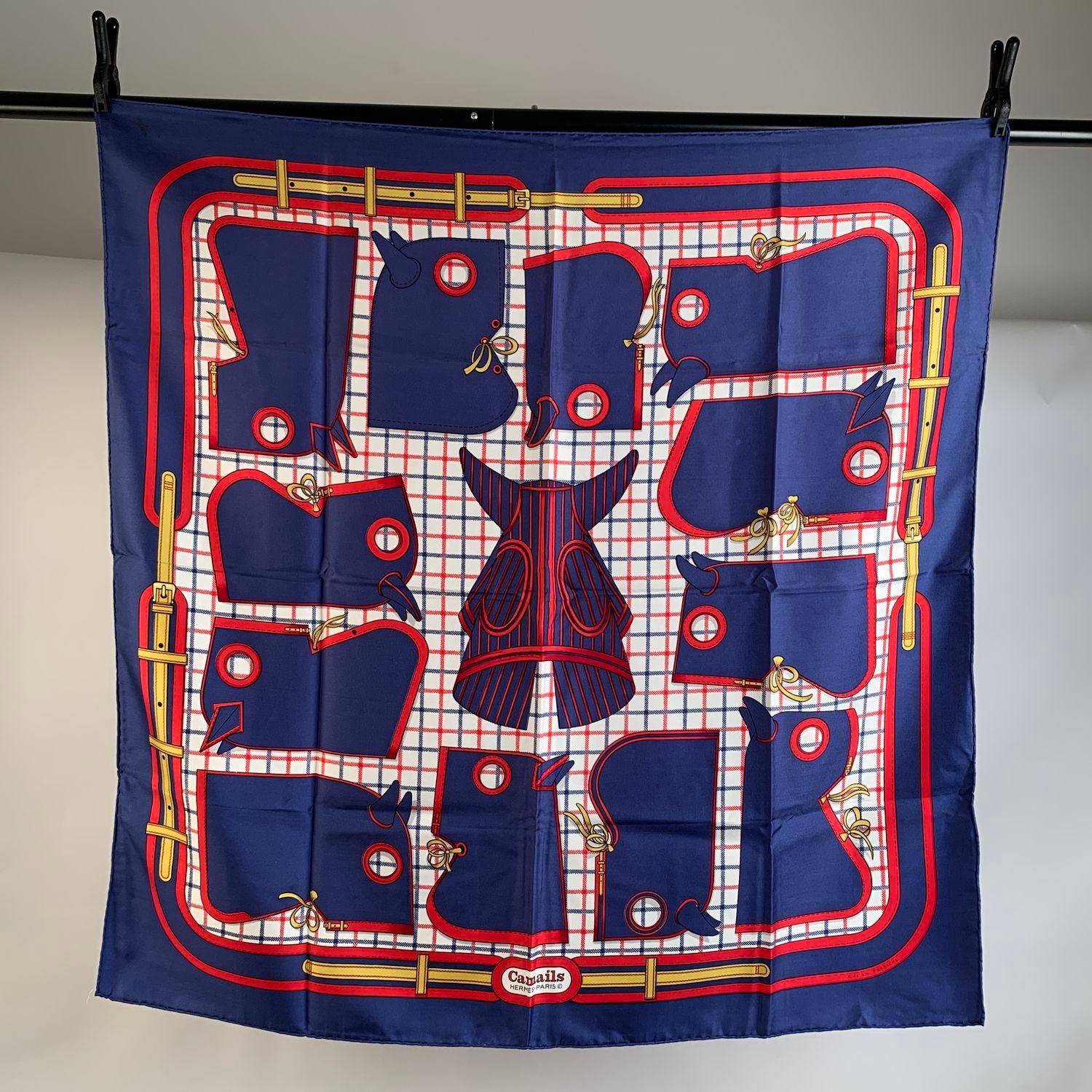 Beautiful Hermes 'Camails' silk scarf designed by Francoise de la Perriere and originally issued in 1974. The design depicts some horse hoods in blue and red color against a checkered white background. Blue border. Hand rolled edges. Measurements: