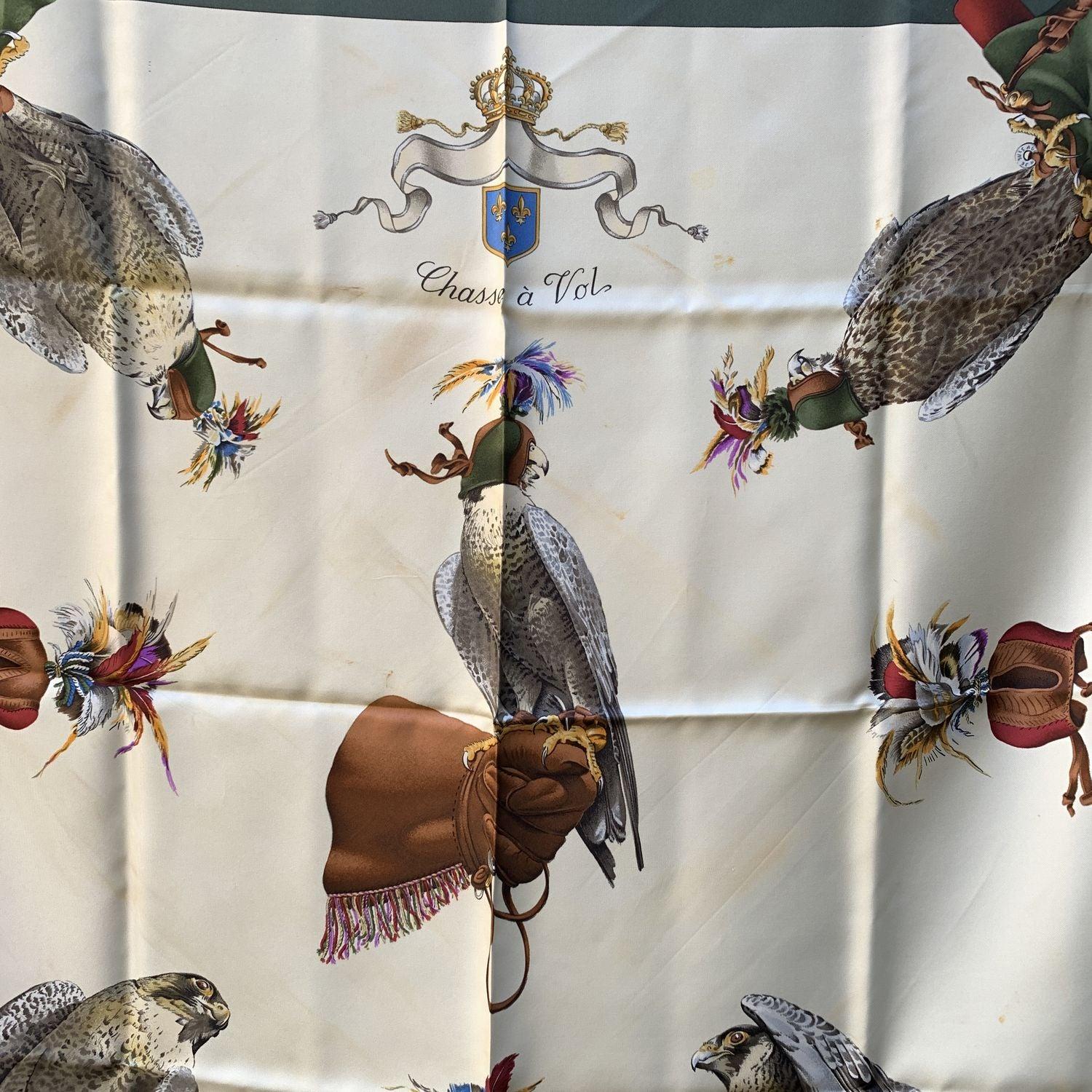 Hermés 'Chasse a Vol' silk scarf. The scarf was was designed by Henri De Linares in 1962. The scarf depicts birds on beige background and framed in dark green borders. The 'HERMES Paris' with copyright symbol is located on the bottom. 100% Silk.