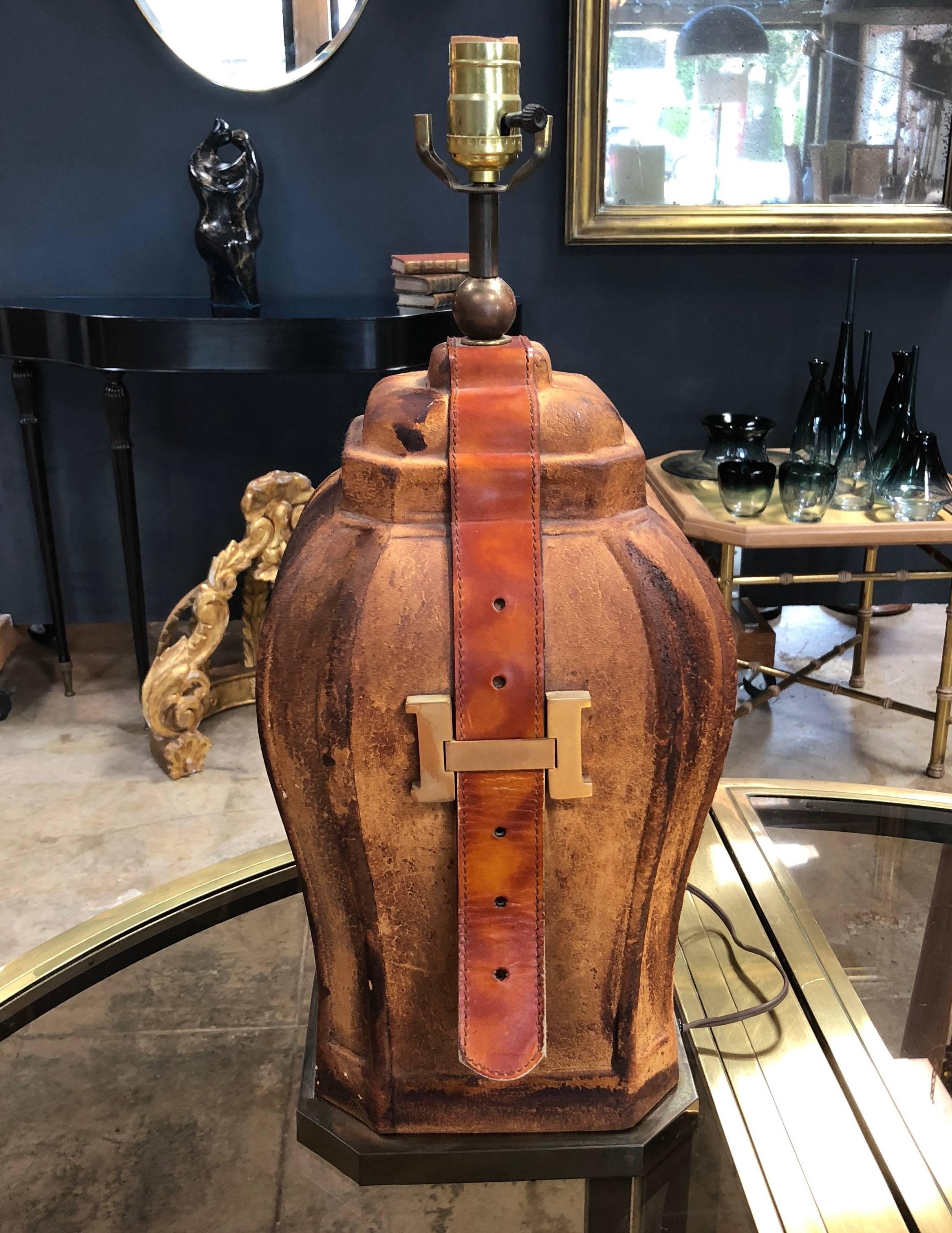 Chic and rare table lamp!
Featuring a particular unique form with sides covered in earthen toned medium brown leather.
With 