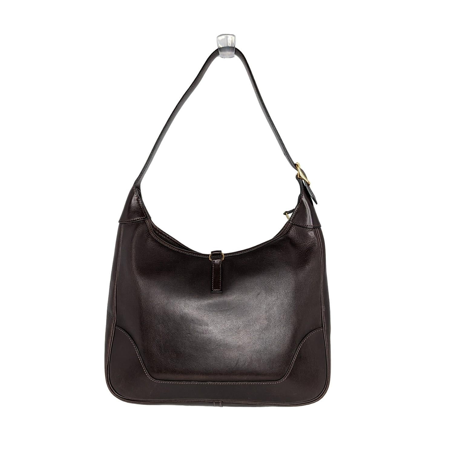 This stylish shoulder bag is crafted of textured box Calf leather in dark brown. The bag features a looping leather shoulder strap with a cross-over strap and a polished gold-tone clasp lock. The inside of the Trim is a pretty free space, with one