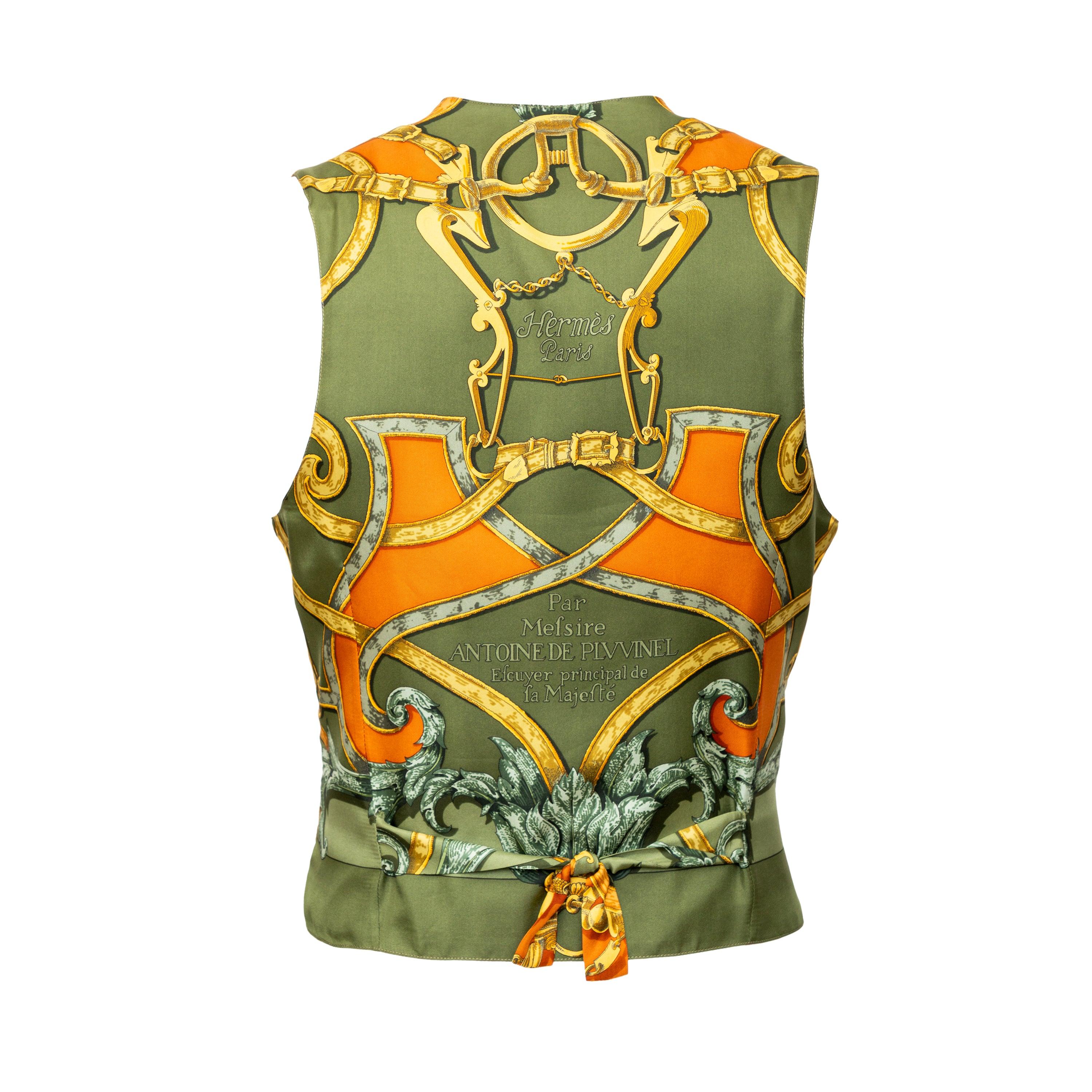 The Hermès Vintage Vest from the 90s is an iconic addition to any wardrobe. Made with olive green cotton and a silk printed back, this vest features a button front and logo-embossed acetate lining. The quilted front adds texture, and the V neck and