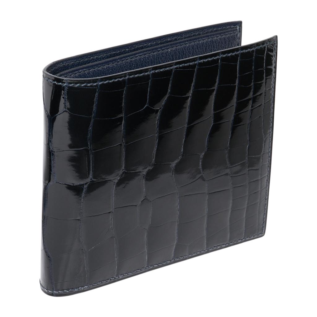 Guaranteed authentic Hermes Men's MC2 Copernic compact bi-fold wallet featured in Blue Indigo Alligator.
Interior is chevre with eight credit card slots, two flat pockets and one paper money slot.
Sleek clean lines.
HERMES Paris Made in France on