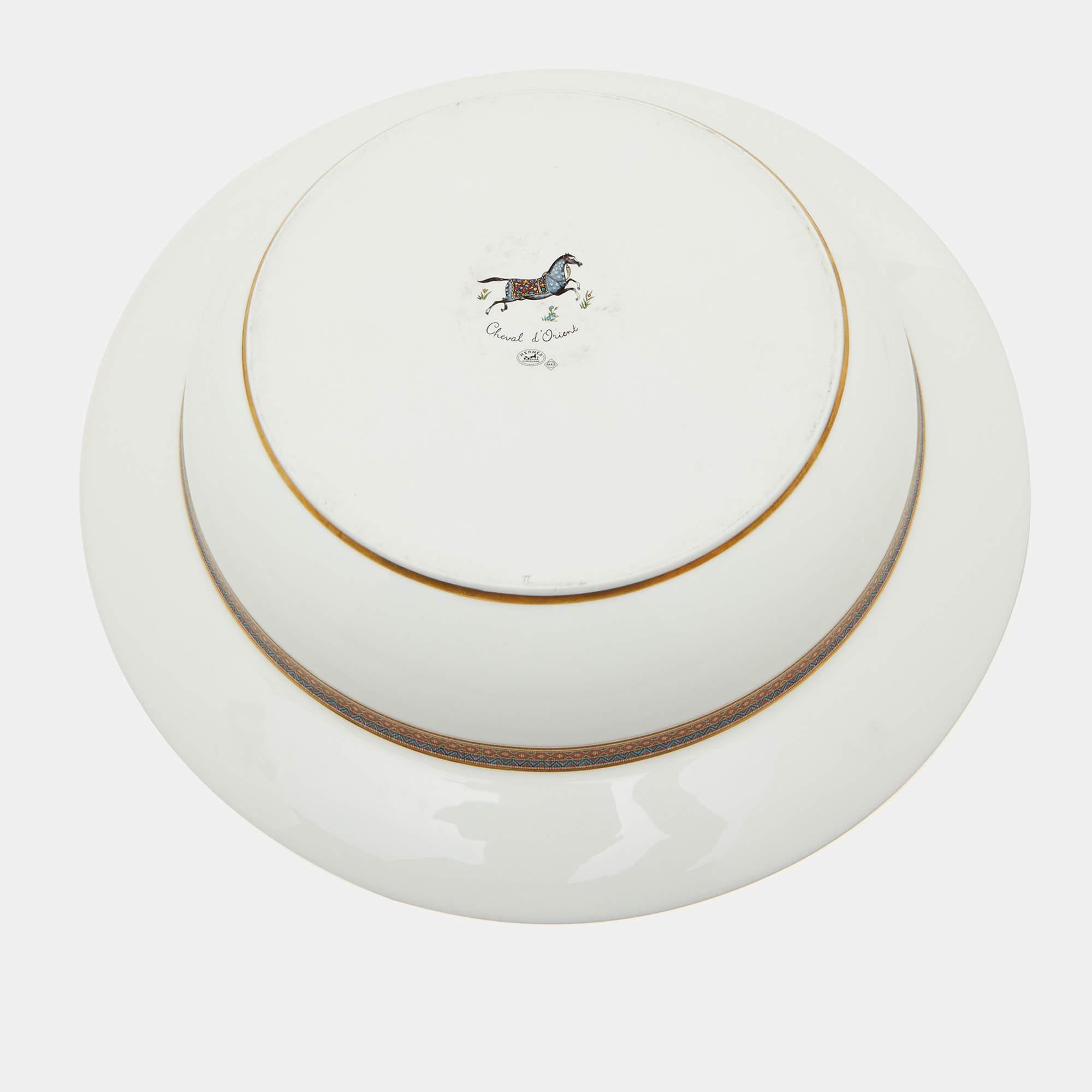 The Hermès centerpiece platter set showcases refined luxury. Crafted with pristine white porcelain, each platter features an exquisite Cheval d'Orient motif, capturing equestrian elegance. Ideal for elegant entertaining, this set of 2 platters adds
