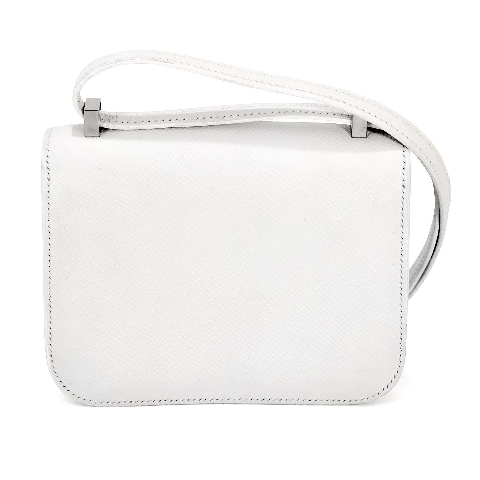 This authentic Hermès White Epsom Leather Micro Constance is in new condition. One of Jackie Kennedy’s favorite Hermès styles, she was often photographed wearing one of the many in her collection. This snowy white version is striking in the micro