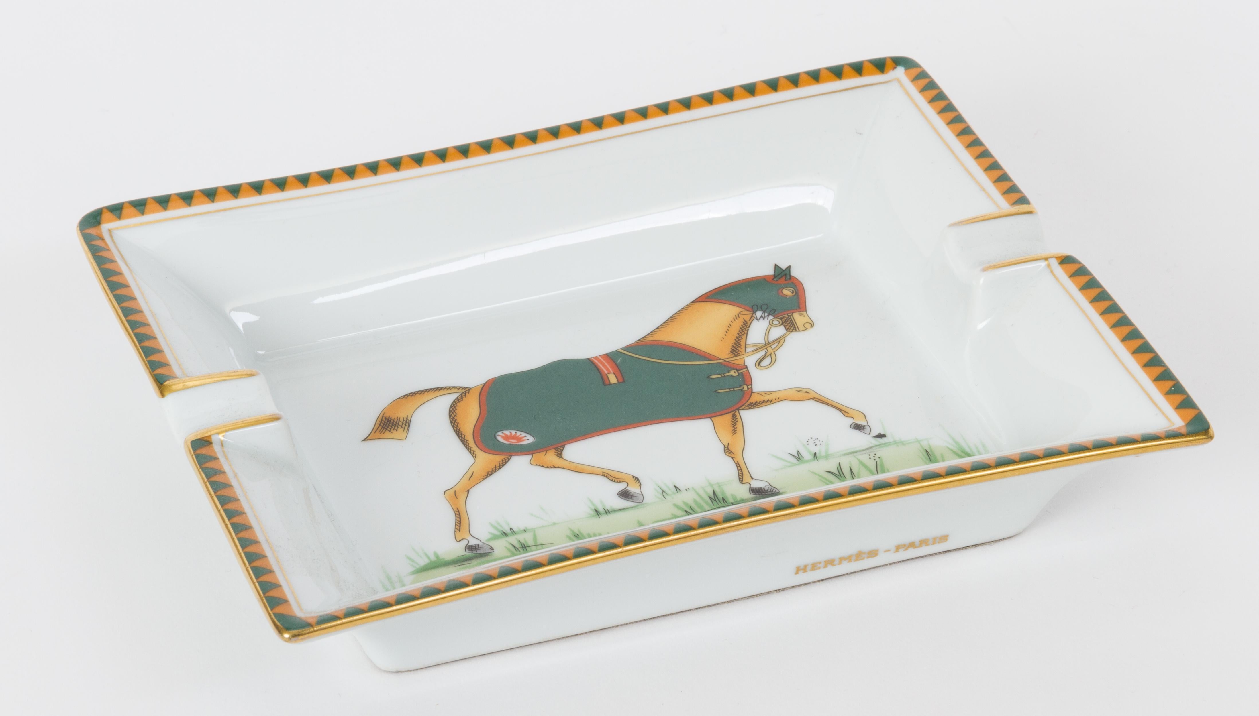 Hermès white porcelain ashtray with a green horse design. Minor wear on suede underside. Does not include box