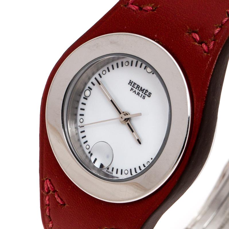 Feel in style with this Hermes watch, designed to radiate luxury in high measures. Made from stainless steel, its round bezel surrounds a white dial featuring luminous markers, a magnified date window and the brand name. The red leather strap adds