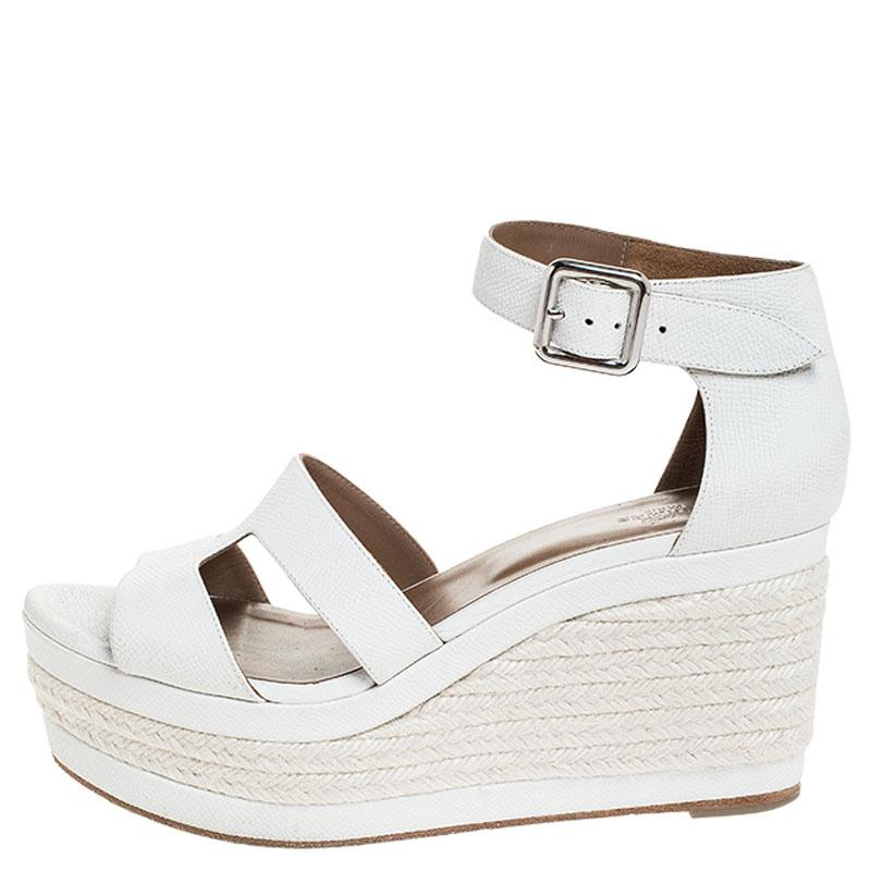 Leave all in awe when you step out in this lovely pair of sandals from Hermes. The pair has been designed with front H straps made from textured leather and covered counters with ankle fastenings. But it is their set of 9 cm espadrille wedges that