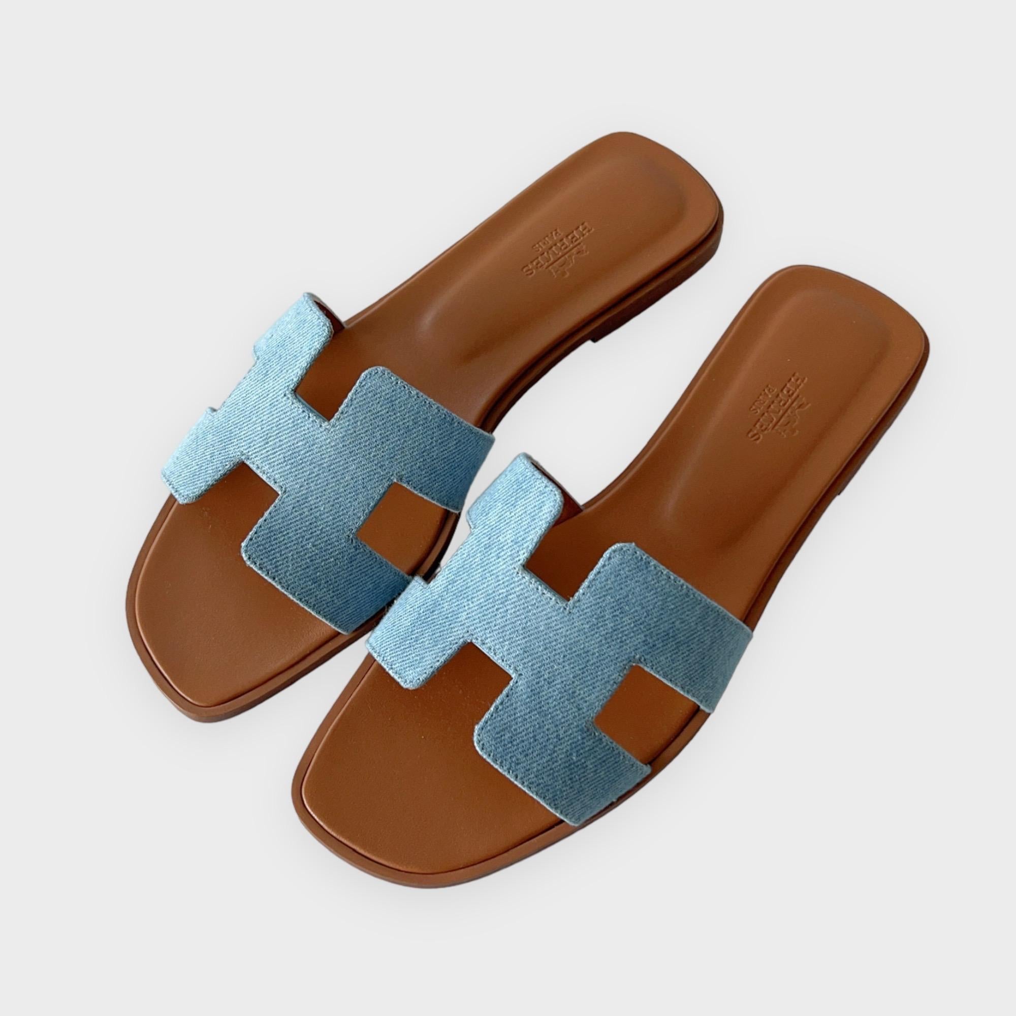 We have a beautiful pair of Hermès Denim Oran Sandals in Bleu Clair featuring the iconic H cut out. Classic, chic and comfy is how we would describe the Oran Sandal. A great pair of footwear for everyday wear. The Denim style in Bleu Clair is new