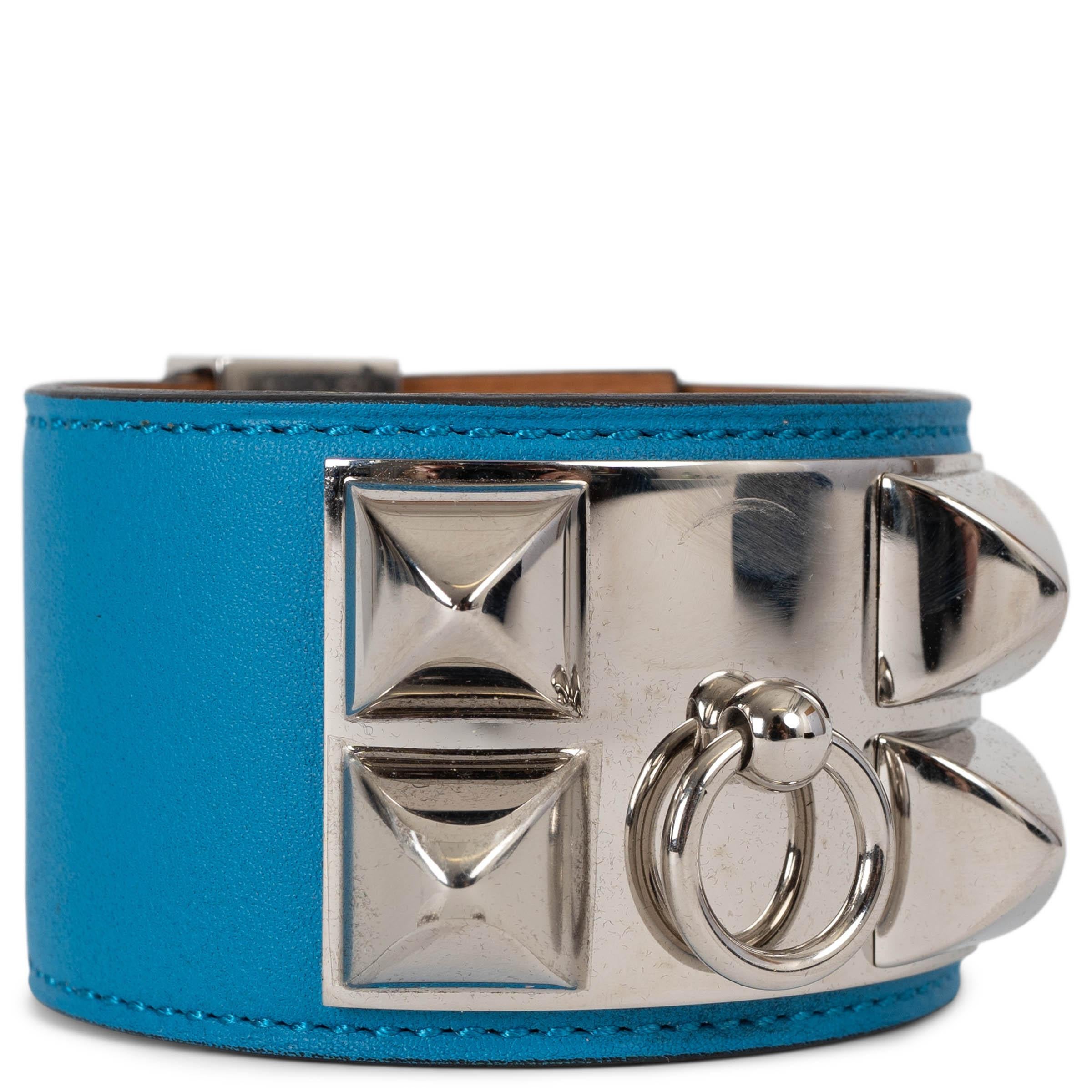 This 100% authentic Hermès Collier de Chien cuff bracelet in Bleu Zanzibar blue Veau Swift leather is a bold statement piece, celebrated for its structured design and luxurious craftsmanship. Accented with palladium-plated hardware, it features the