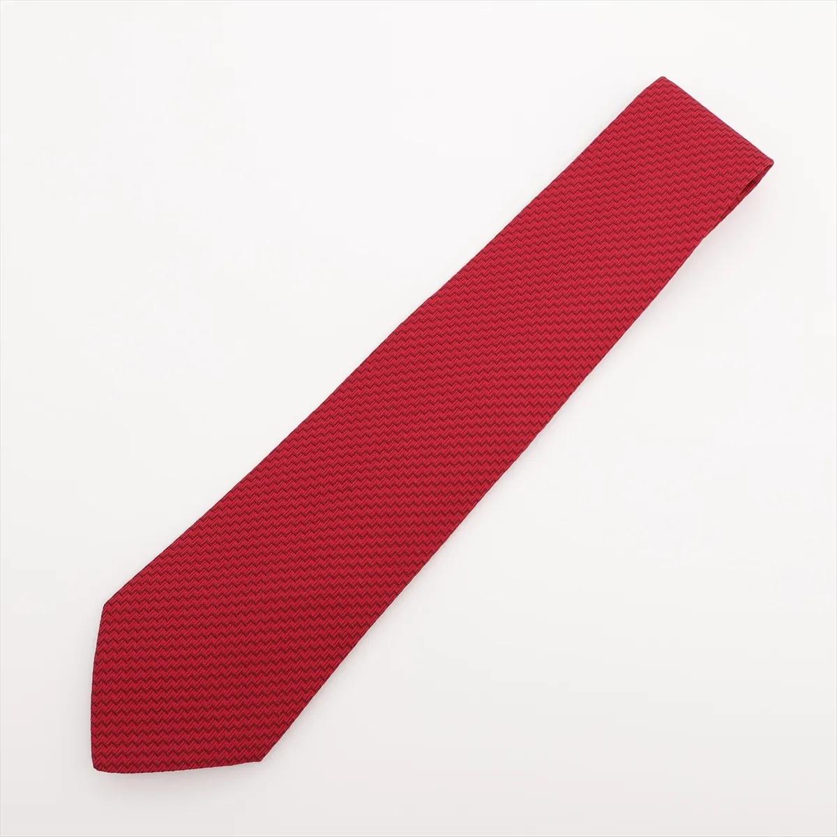 The Hermès Zigzag Silk Necktie in Red is a sophisticated accessory that combines timeless elegance with a modern edge. Crafted from luxurious silk, it features an intricate zigzag pattern that adds texture and depth to its bold red hue. The refined