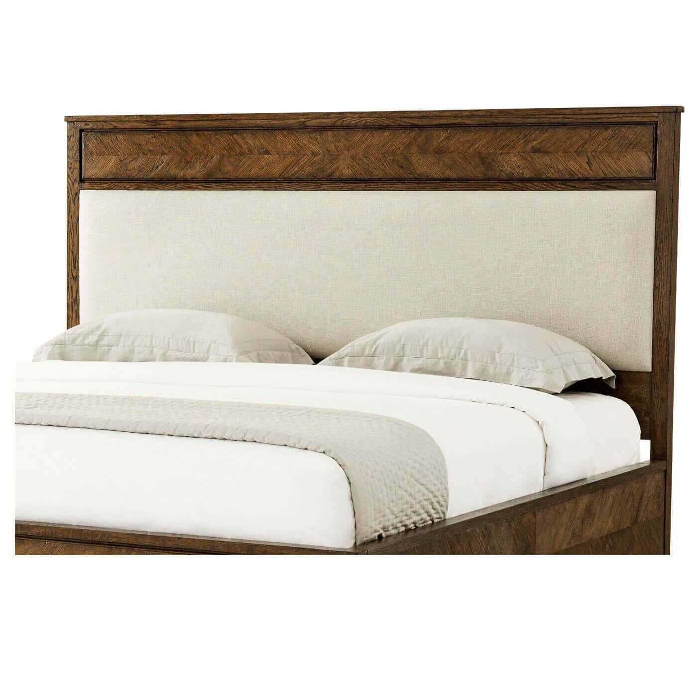 Ein California King Bett aus rustikaler Eiche mit Parkett. Es hat eine klassische Silhouette mit einem gepolsterten Paneel-Kopfteil mit einer gerahmten Eichenholz-Seitenleiste und konisch zulaufenden Beinen. 

Abmessungen: 77,5