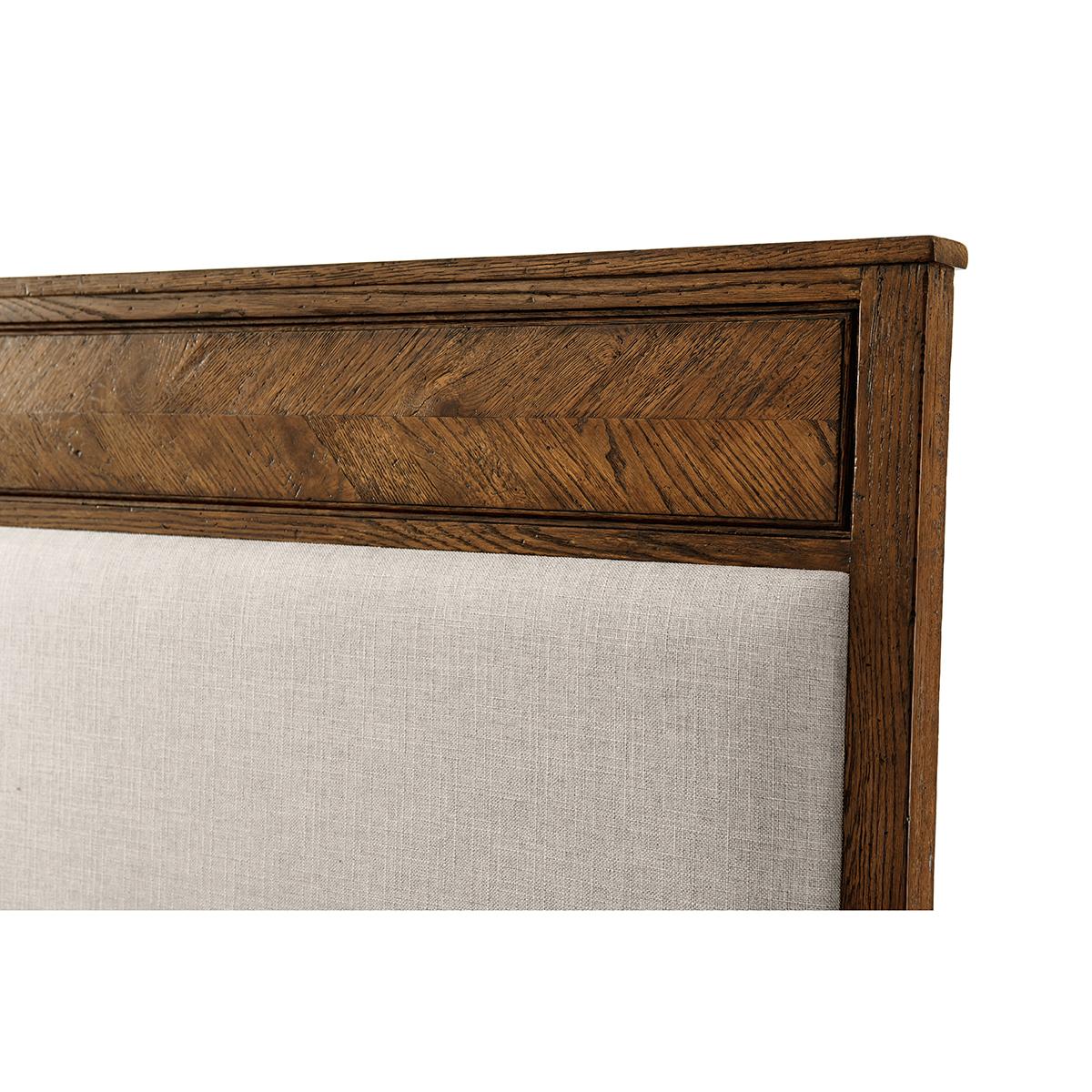 A Herringbone parquetry king bed crafted from rustic oak. This beautiful bed has a hand-carved starburst design. It has a classic silhouette with an upholstered panel headboard with a framed oak side rail and tapered finish leg. 
Shown in Dusk