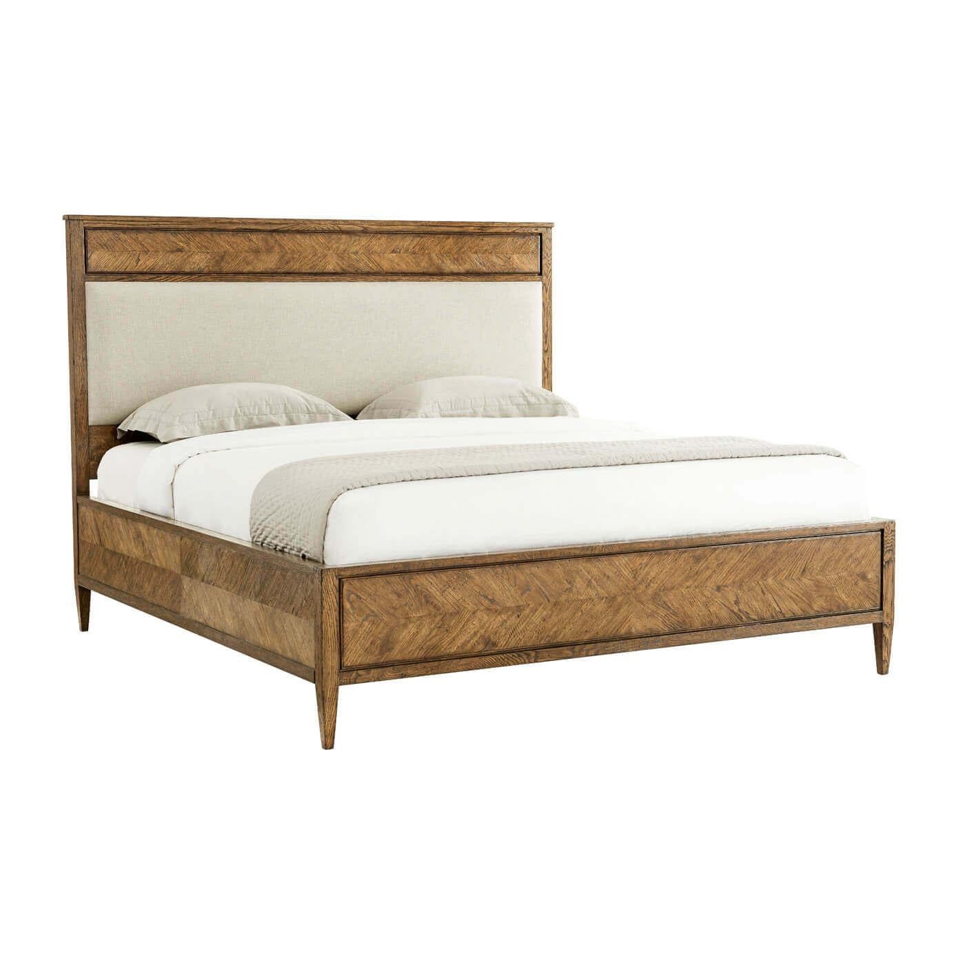 A Herringbone parquetry king bed crafted from rustic light oak. This beautiful bed has a hand-carved starburst design. It has a classic silhouette with an upholstered panel headboard with a framed oak side rail and tapered finish leg. 
Shown in