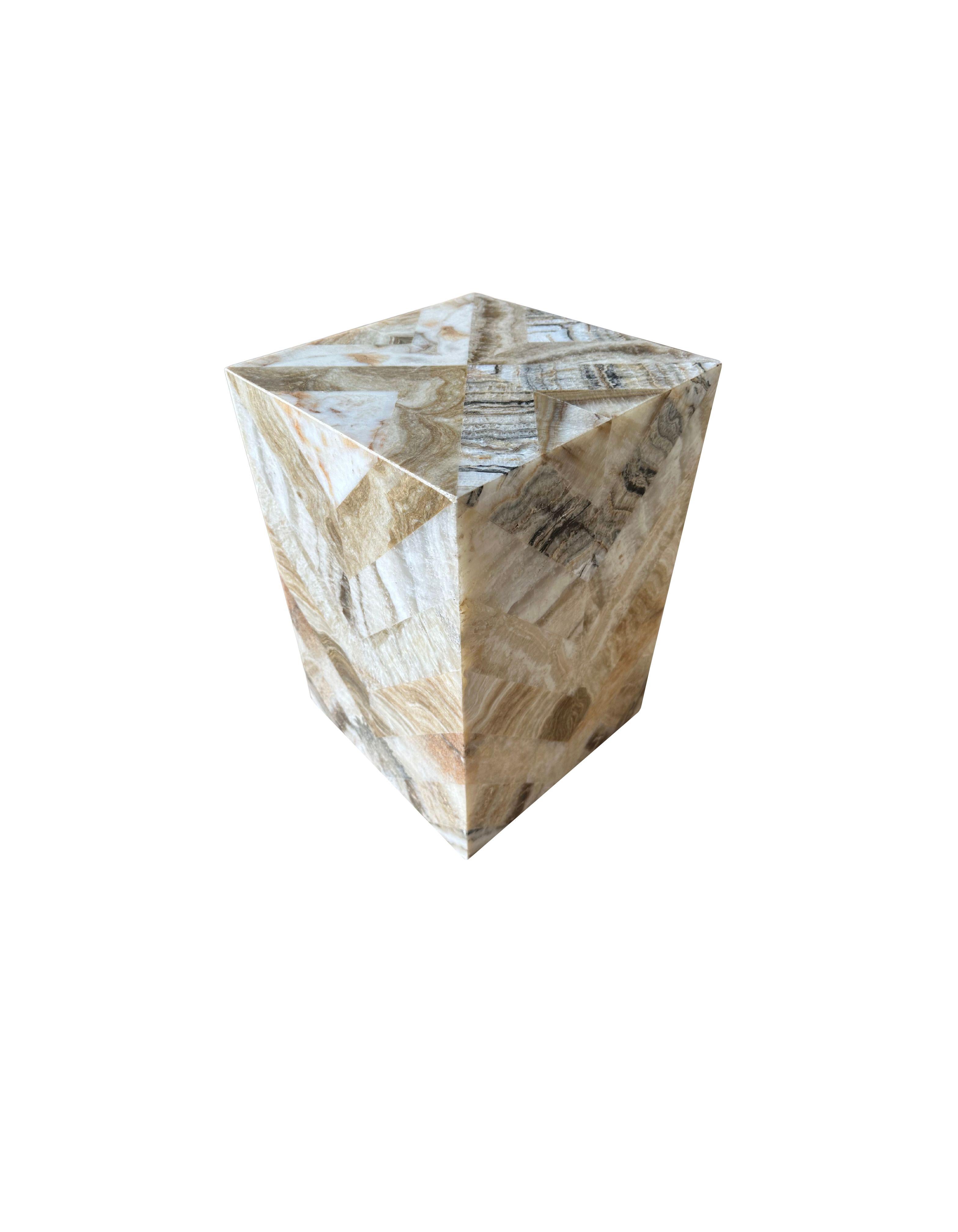 A marble side table or pedestal with wonderful textures and shades. It features a herring bone pattern, with smaller marble cut outs that have been molded together. Hand-crafted by local artisans on the island of Java, this is a wonderful object to