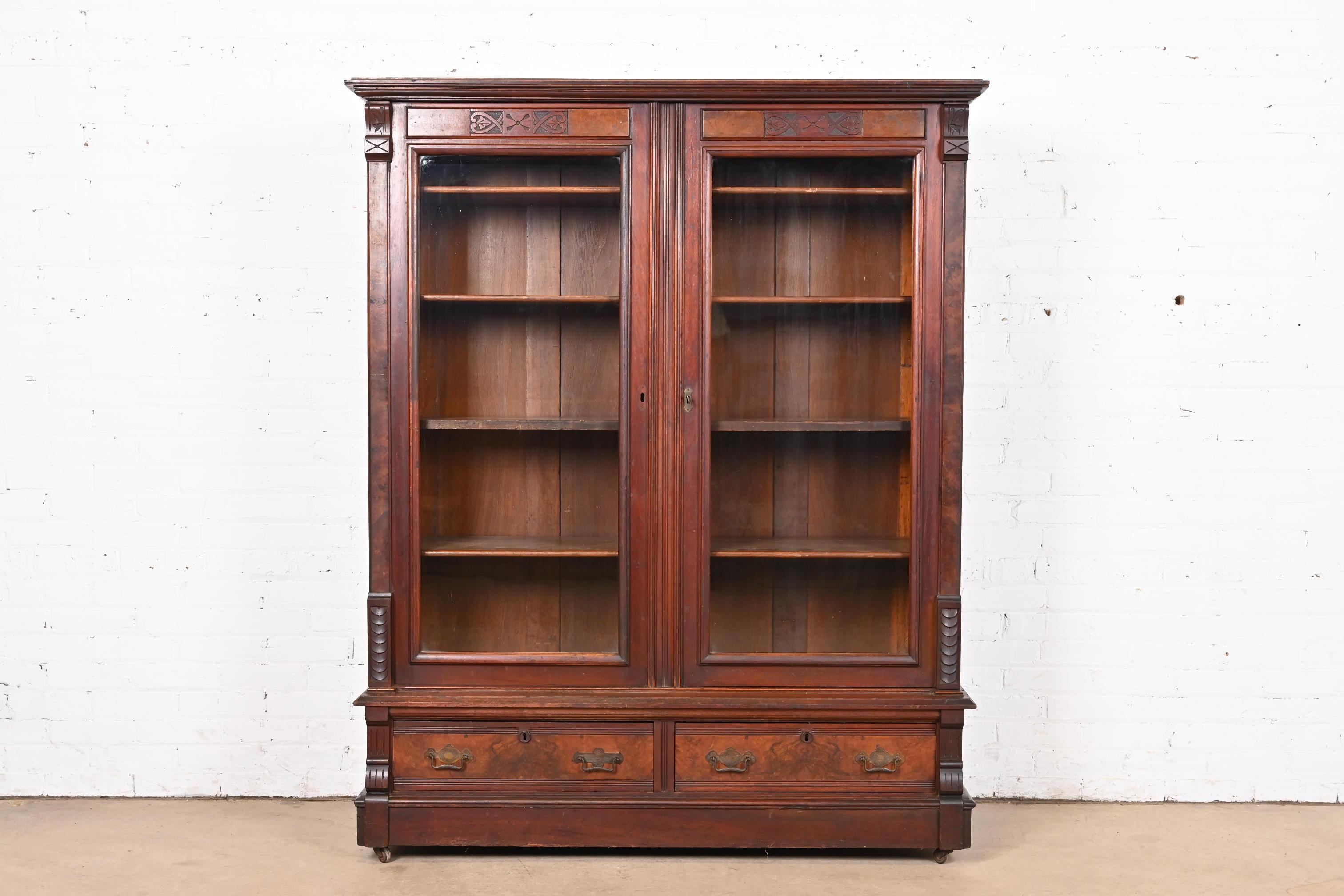 An outstanding antique Eastlake Victorian bookcase cabinet

In the manner of Herter Brothers

USA, Circa 1880s

Carved walnut with burled walnut front, glass front doors, and brass hardware. Cabinet locks and key is included. Shelves are