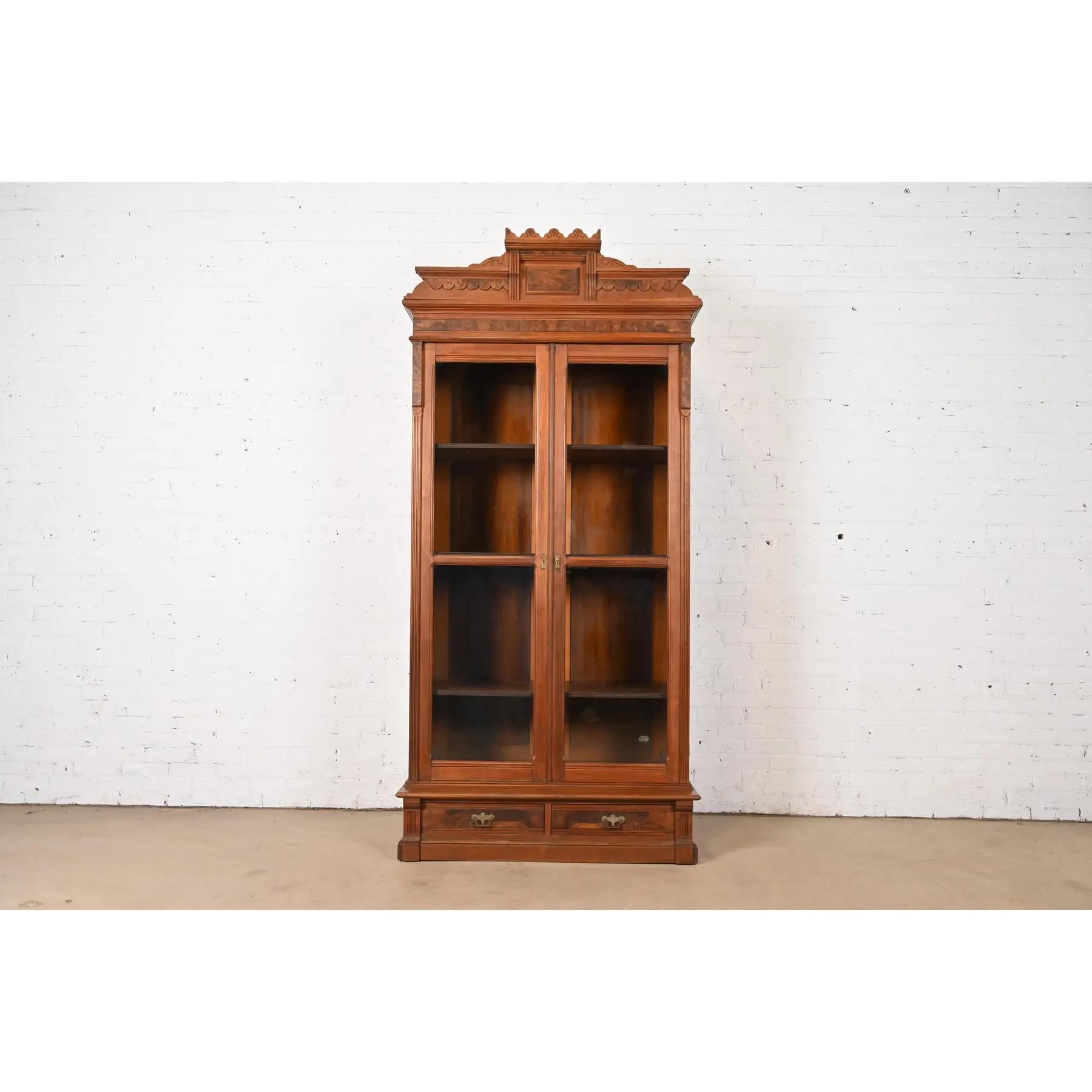 An exceptional antique Eastlake Victorian bookcase

In the manner of Herter Brothers

USA, Circa 1880s

Carved walnut, with glass front doors, burled walnut panels, and original brass hardware.

Measures: 44.25
