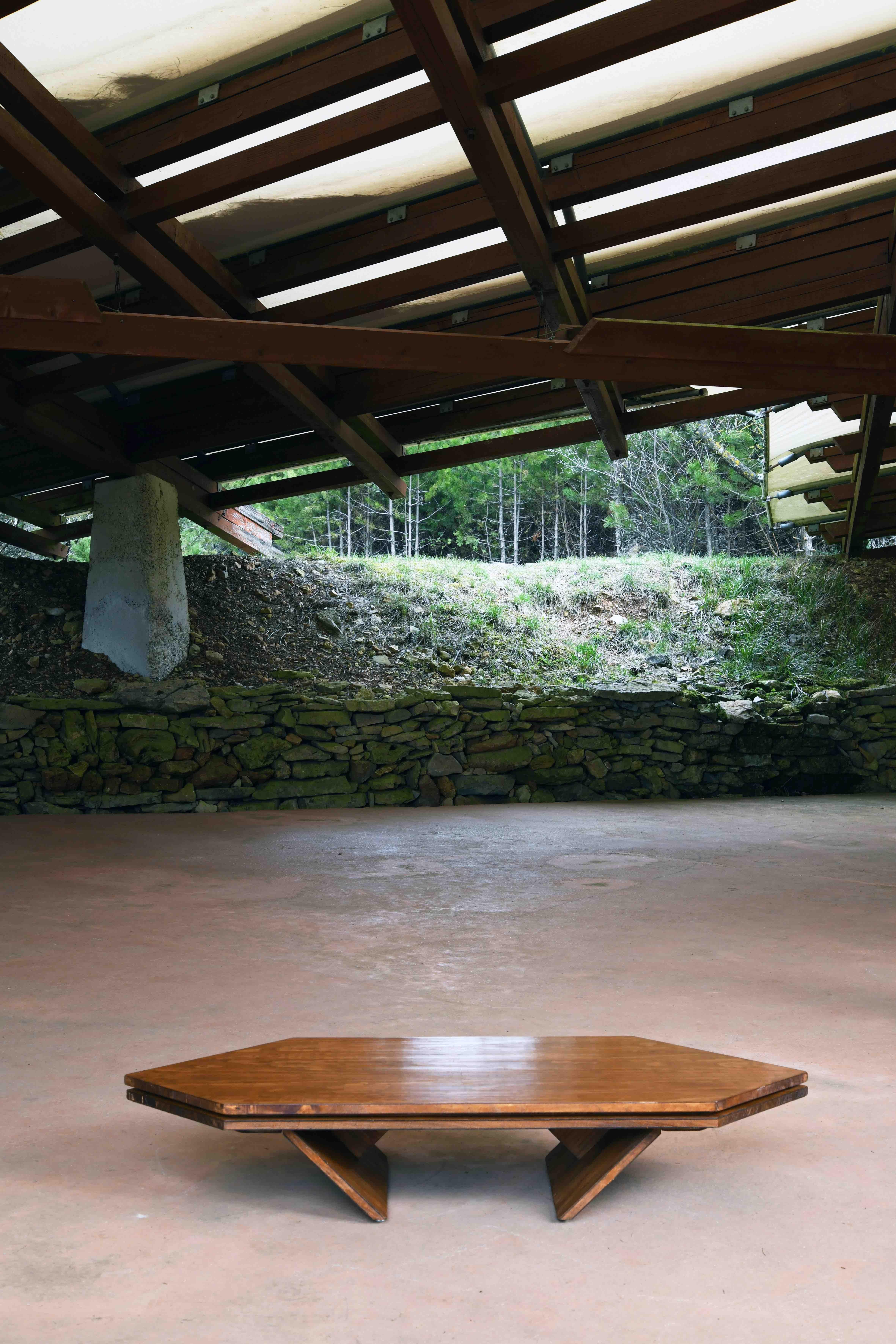 Table basse hexagonale en pin d'Oregon sur bois structuré. La table angulaire se caractérise par des points à 45 degrés aux deux extrémités du plateau, avec des pieds angulaires similaires pointant vers l'intérieur, prolongeant le plateau et le fond