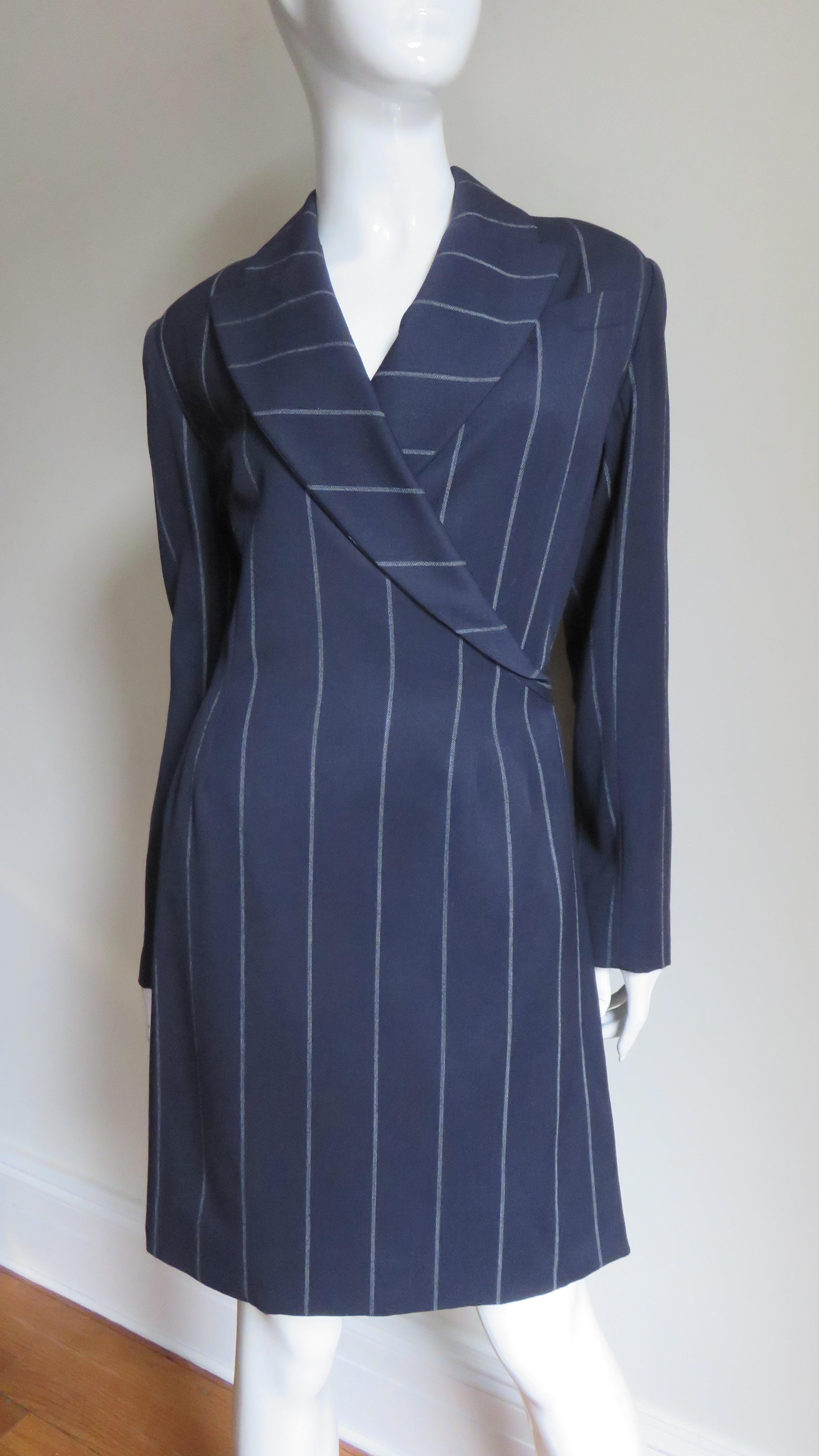 A great off white striped navy blue wool dress from Herve Leger.  The semi fitted wrap style dress has a breast pocket, peaked lapels and a double vent on top of a single vent in the back skirt for a bit of a twist. The dress is fully lined, has