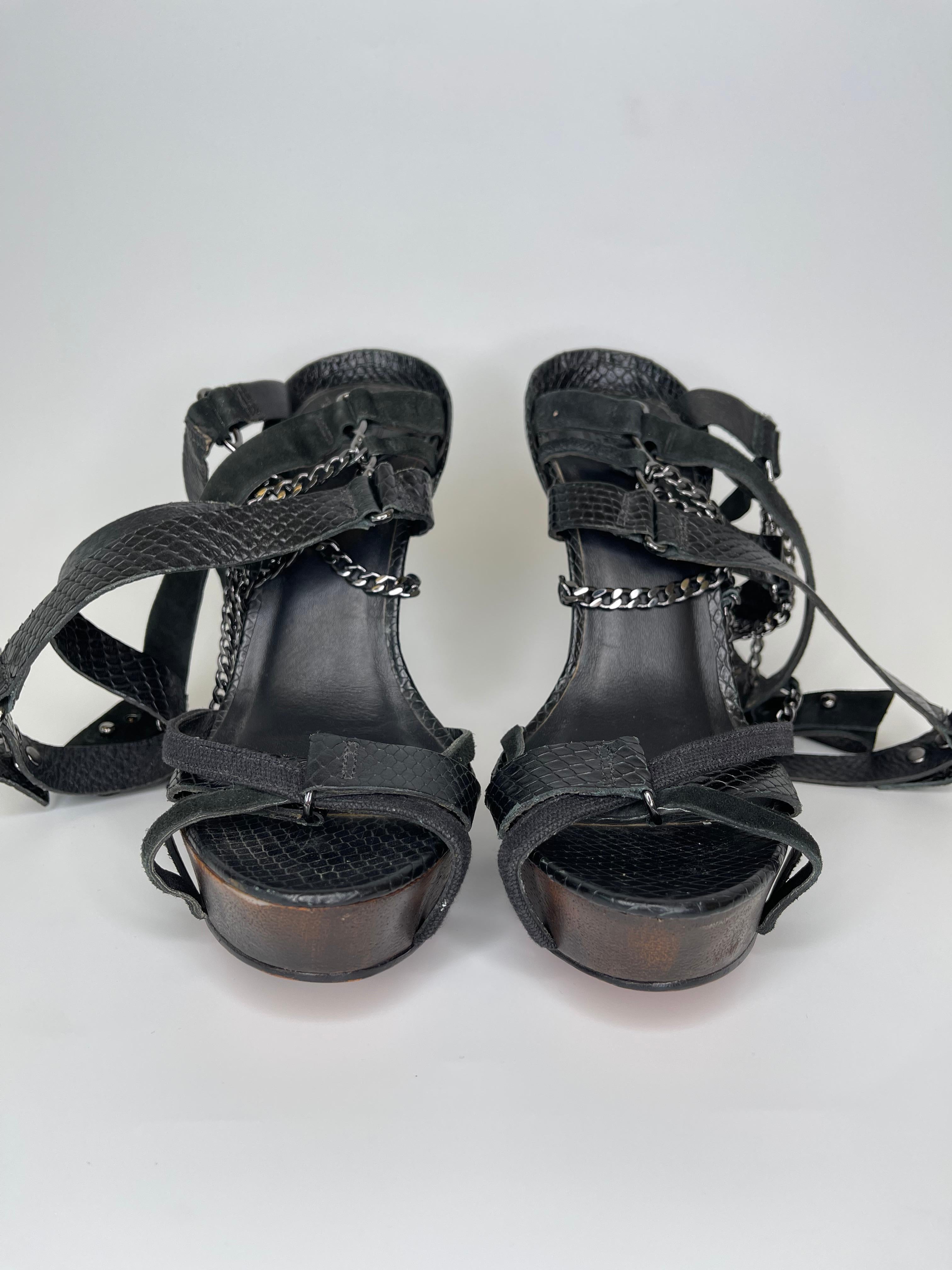 This Herve Leger Black Python Sandal consists of a classic black embossed leather with a snakeskin-like print. Open toe with multiple straps and chains to hold in place. Silver Herve Leger logo located on the back of the platform. 

COLOR: