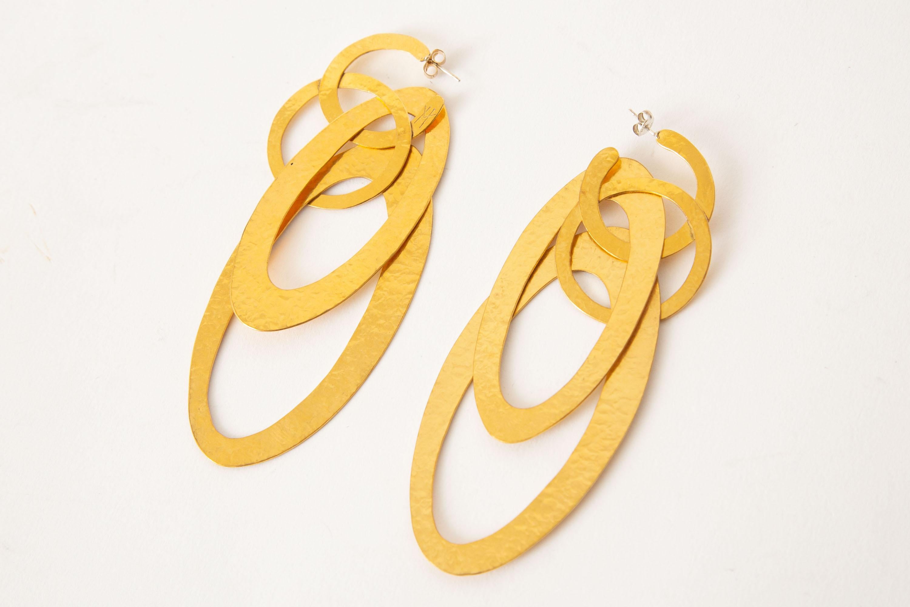 These dramatic french geometric hand wrought gold plated and hand hammered pierced earrings are by Herve Van der Straeten. They are long dangle earrings with angled circles; geometric with a twist of ancient civilizations brought to a modern look.