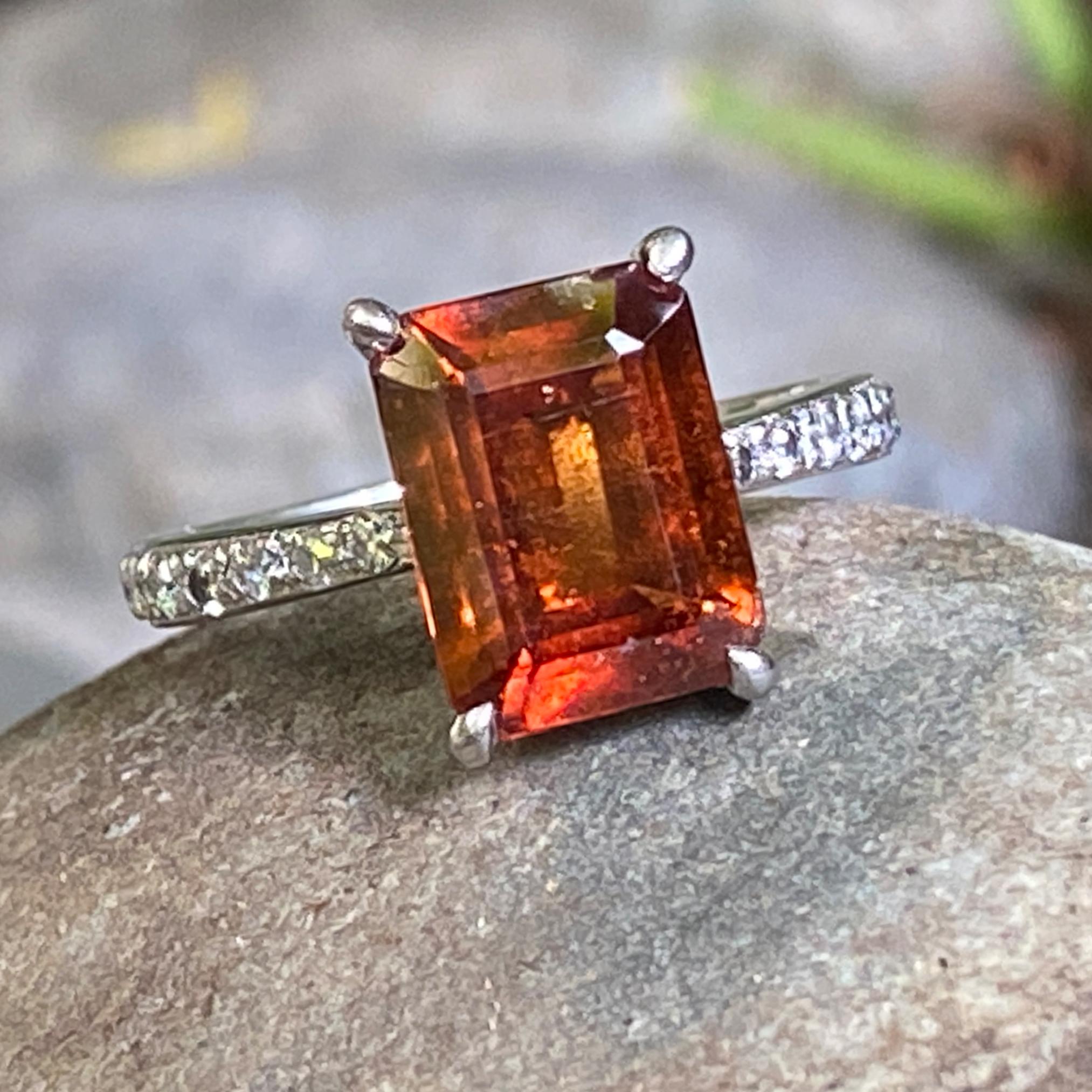 This is simple little engagement ring makes a great delivery system for a vivid hessonite garnet.  

The ring was probably made in the 1970s or 1980s.  It is solid platinum with twenty pavé full-cut diamonds on the shoulders.  The diamonds are of