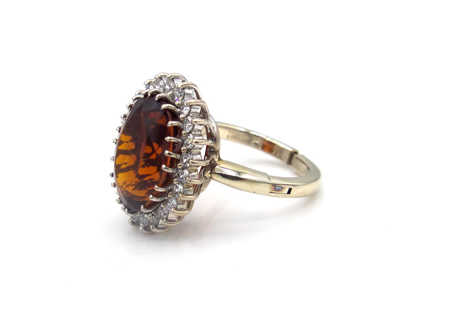 This oval-faceted cinnamon hessonite garnet cocktail ring is set in a 14 K gold band and is surrounded by 22 round cut diamonds. The adjustable mechanical band on this ring makes it a perfect fit for many. 

7.4 g

Size 5-7.5