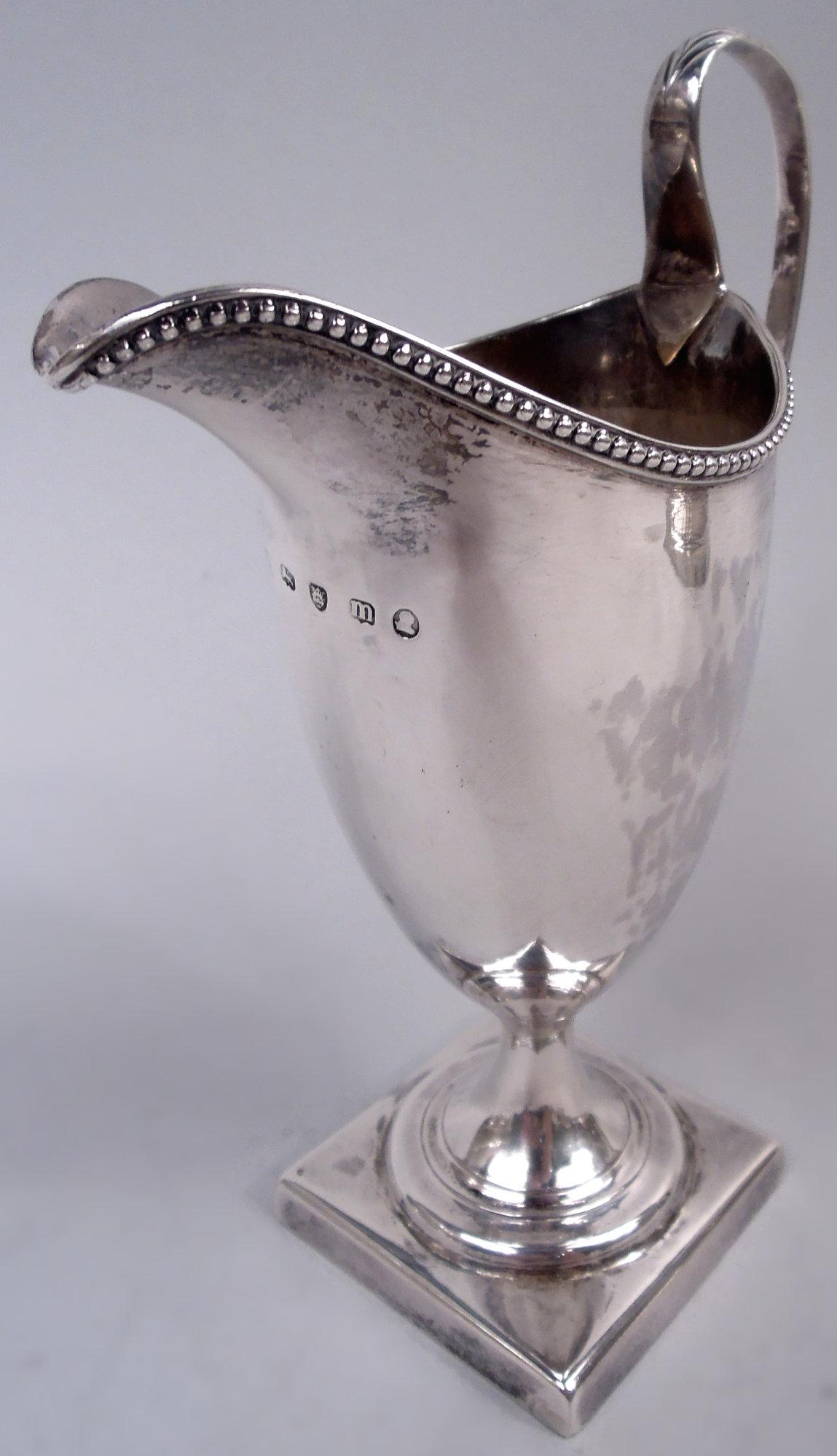Milchkännchen aus Sterlingsilber George III. Hergestellt von Hester Bateman in London im Jahr 1787. Spitz zulaufende Schale auf erhöhtem Fuß, montiert auf quadratischem Sockel; wulstige Helmöffnung und hoher Looping-Griff mit Chevron-Blattkappe.