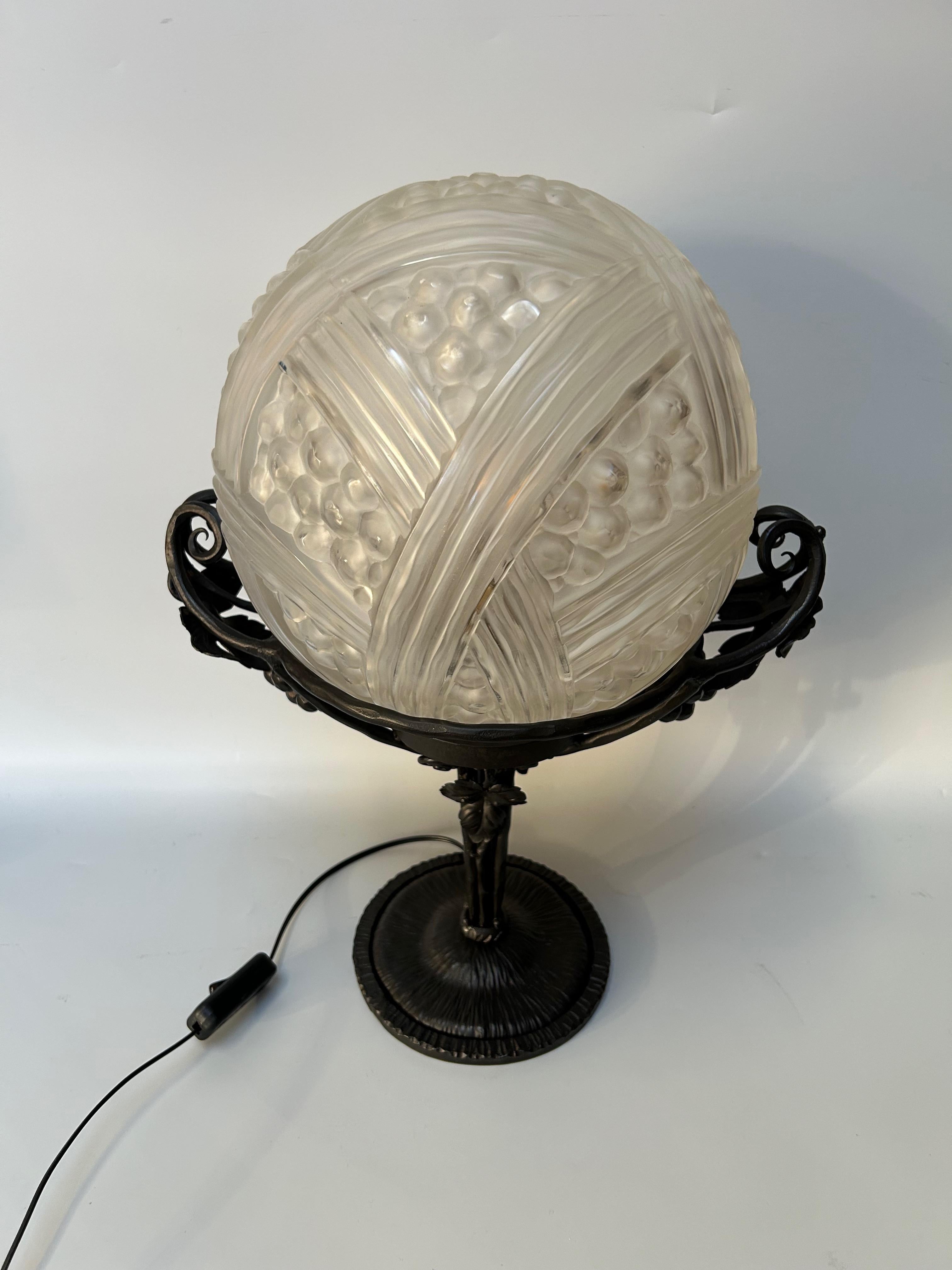 Art Deco lamp circa 1930.
Wrought iron base decorated with bunches of grapes.
Pressed molded glass ball by Héttier and Vincent.
Electrified and in perfect condition.

Total height: 44.5 cm
Base diameter: 16 cm
Ball diameter: 25 cm
Weight: 5.5