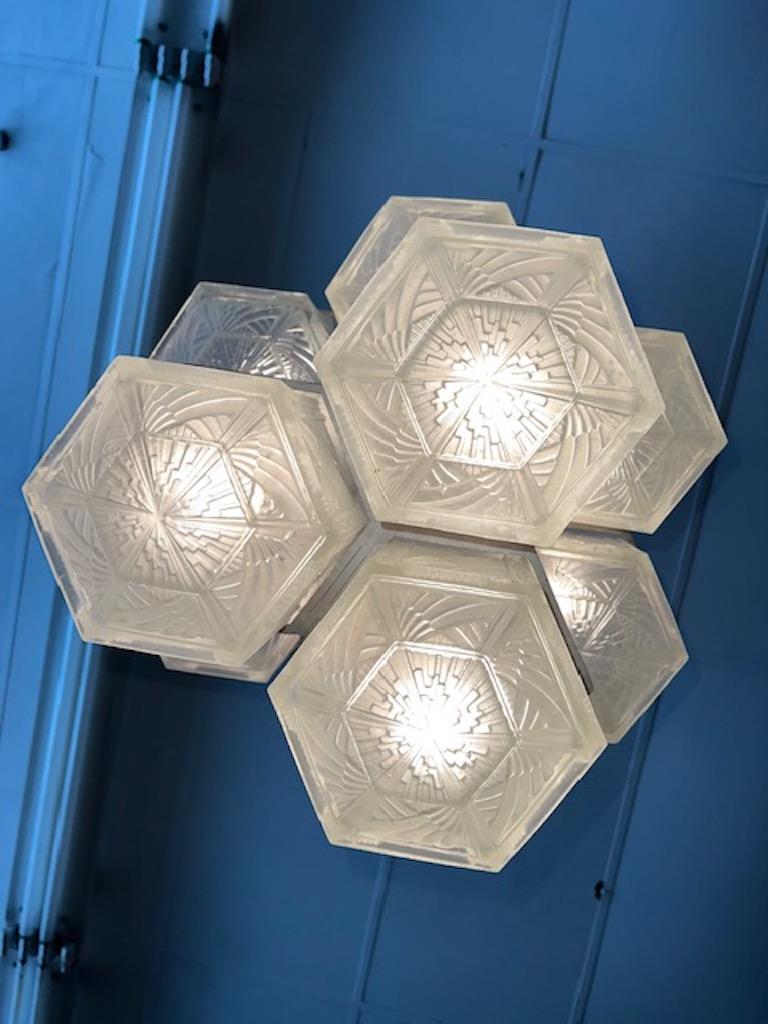 Beautiful Art Deco chandelier is composed out of 9 shades hexagon shaped, made out of frosted glass with polished details. Each of the shades is stamped with designers name. Shades are supported by polished nickel frame. Chandelier is operated with