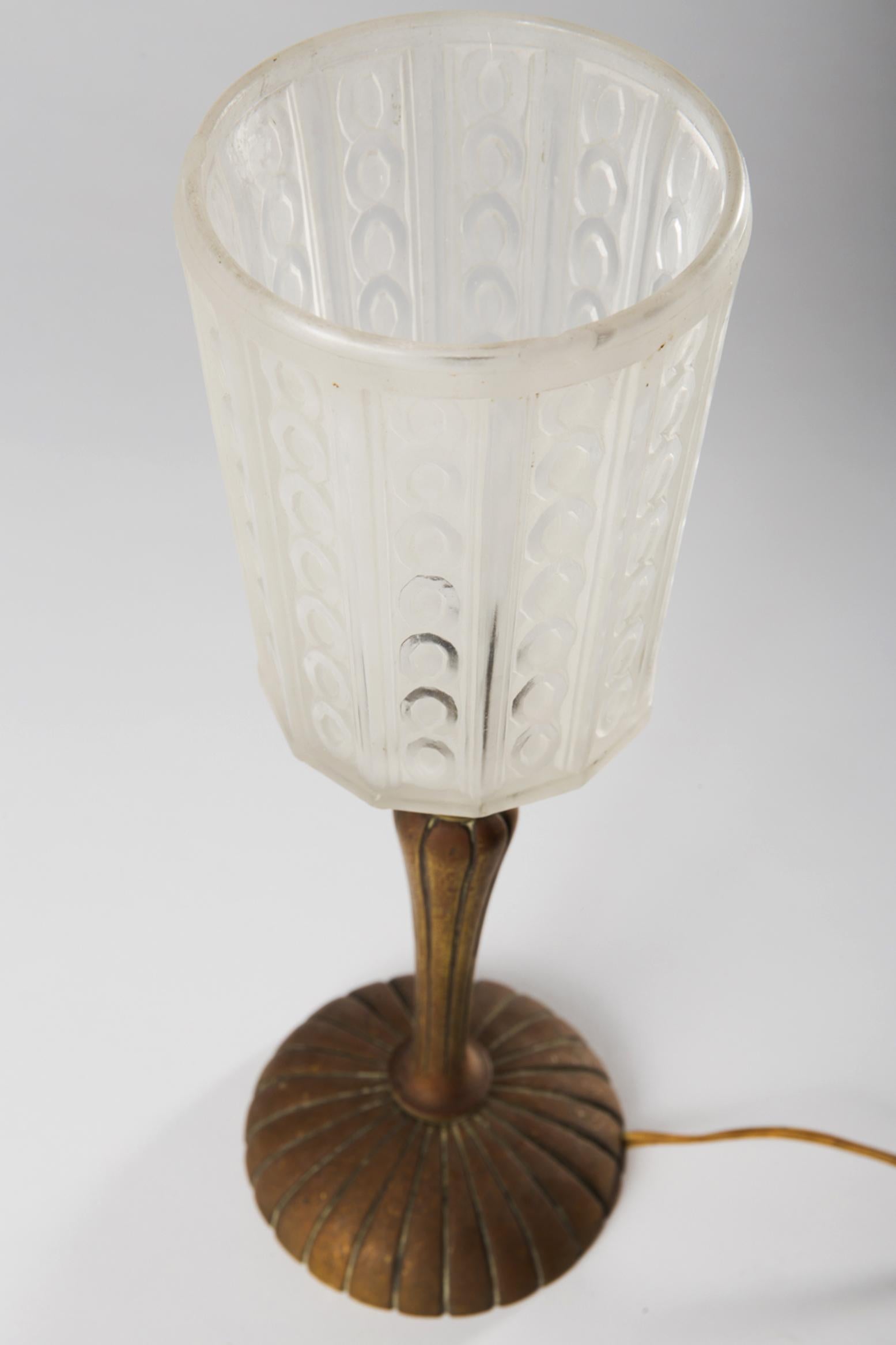Art Deco table lamp by Hettier & Vincent, France from the 1930s.
Pressed glass, metal construction of a baluster-shaped metal base and a slightly conical, dodecagonal glass shade, a focal point, on the screen with maker's stamping, 
Dimension: H