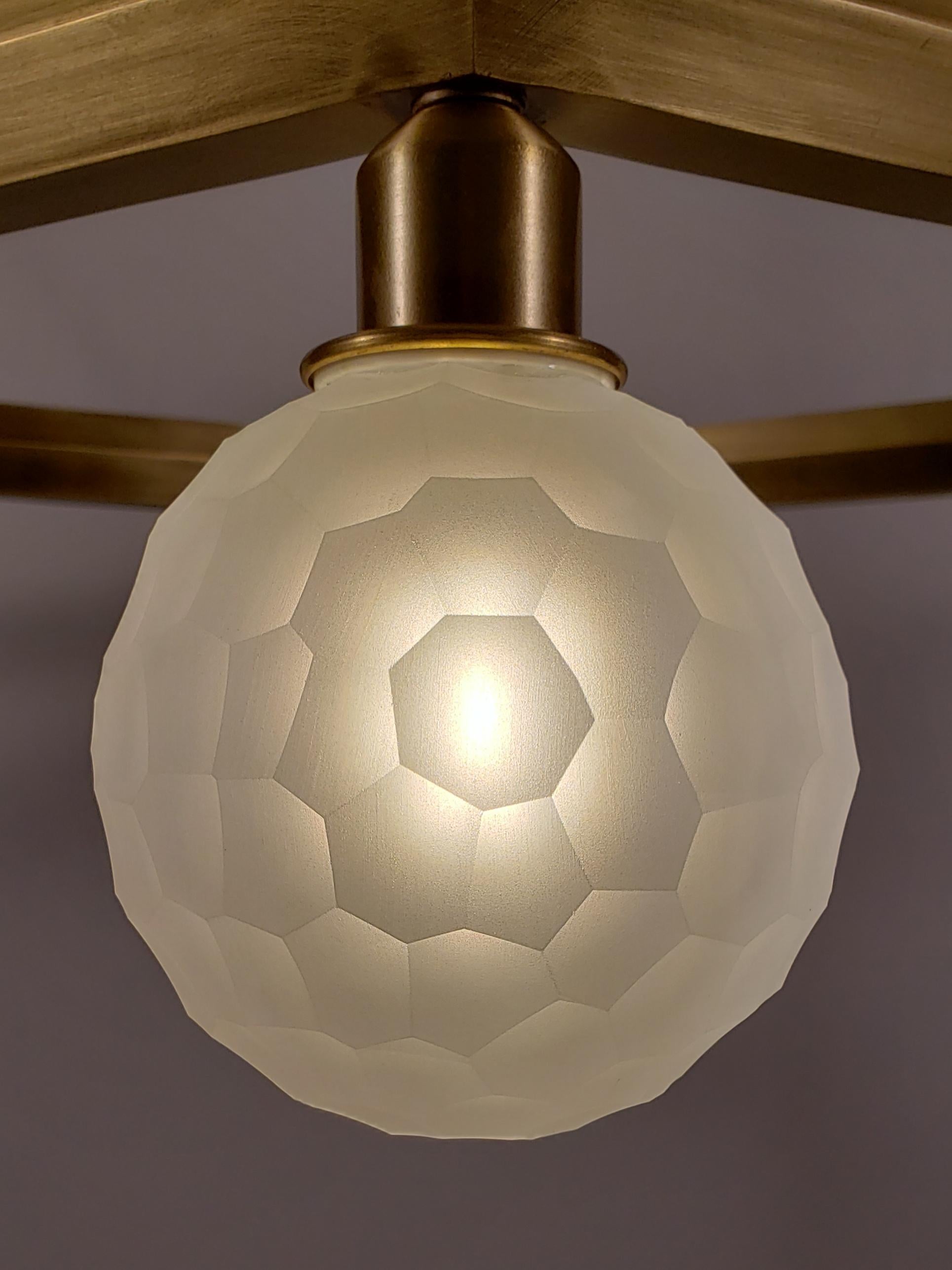 The Hex Series chandelier features six handblown glass orbs strategically arranged on a hexagon shaped frame. Each individual orb is hand carved on a diamond lathe to create the honeycomb, faceted pattern that perfectly compliments the hexagonal