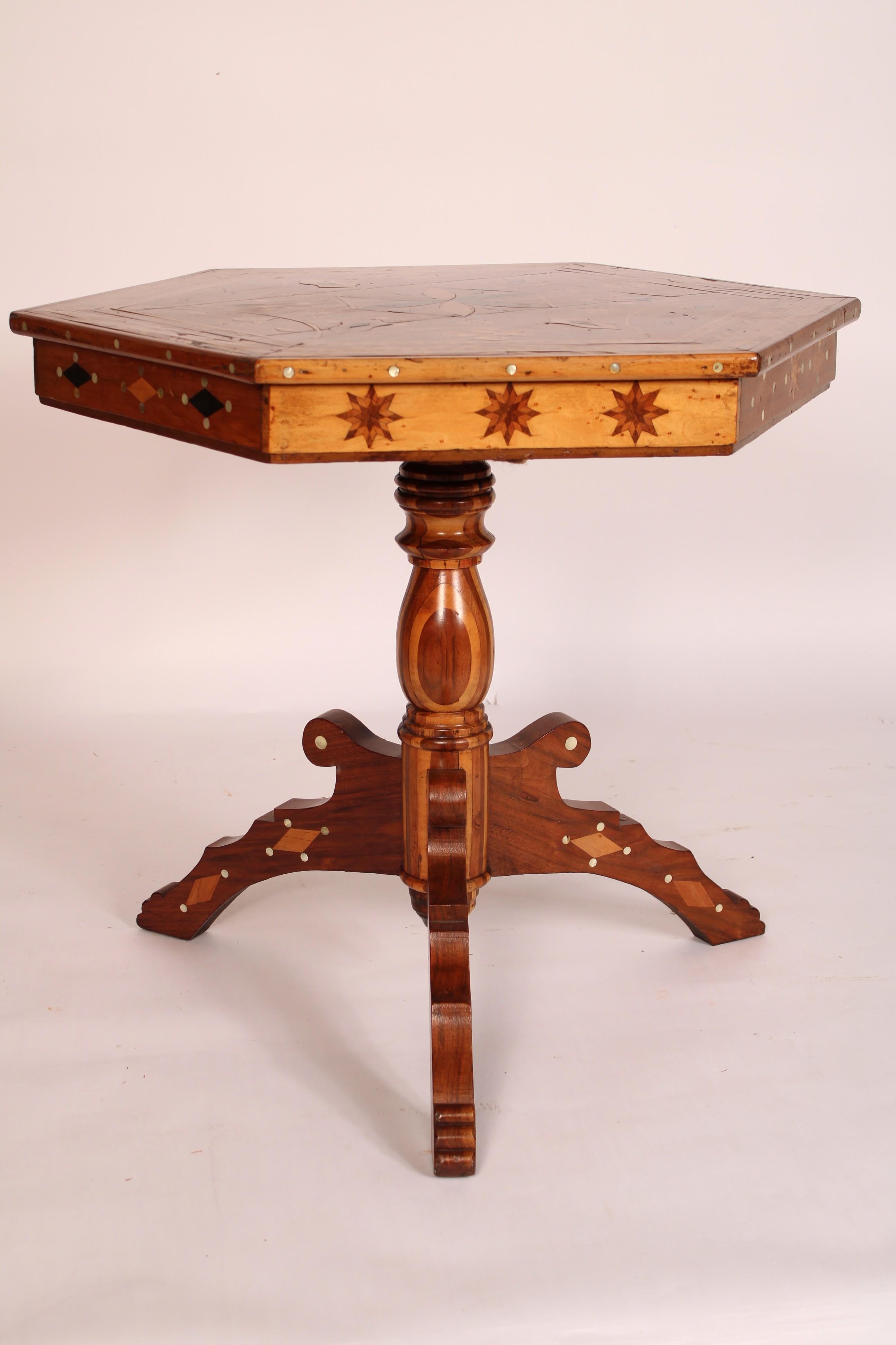 Tavolo occasionale esagonale in stile tramp art, intarsiato in noce, acero, palissandro e madreperla. Con un piano esagonale intarsiato con intarsi in madreperla sui bordi laterali, un grembiule intarsiato con intarsi in madreperla, un piedistallo