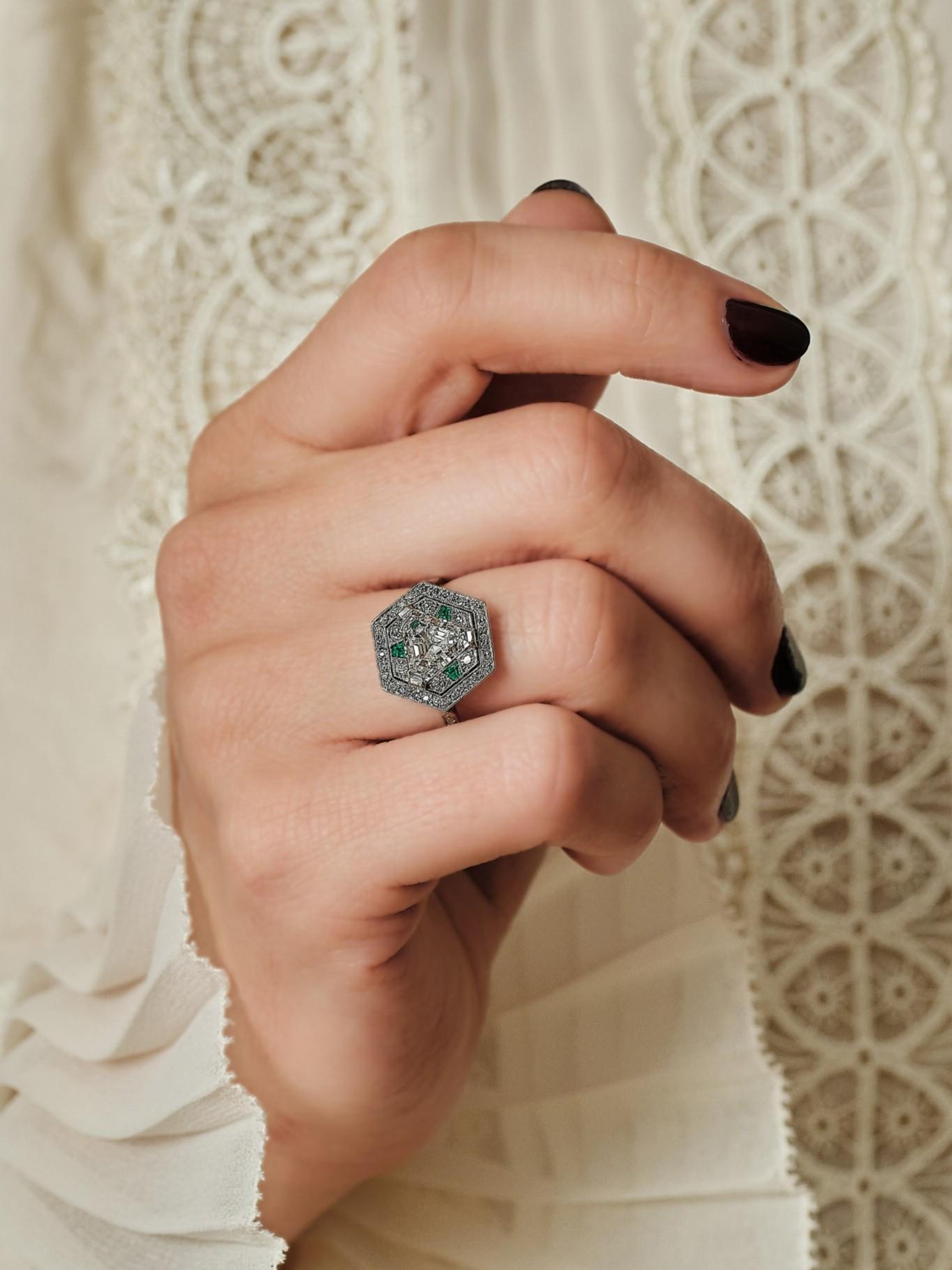 A refined luxurious avant-garde fashion statement. 

Hexagonal, finely openwork ring in platinum 850 thousandths, set with a claw-set triangle-cut diamond in a double setting of old-cut and 8/8-cut diamonds, punctuated by three calibrated emeralds.